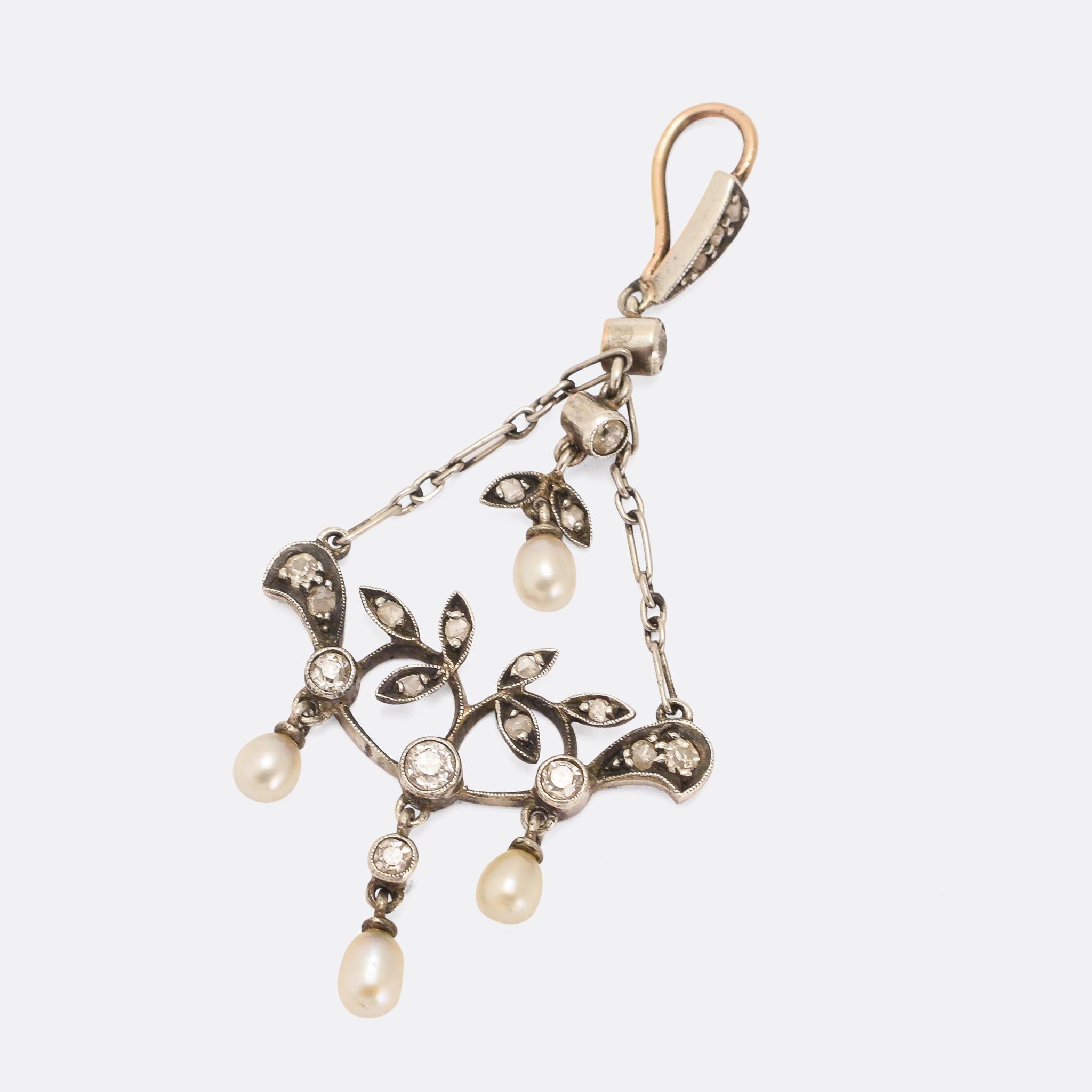 A divine late Victorian pendant set with diamonds and pearls. It was made at the turn of the 20th Century, with foliate motifs and millegrain detailing around the settings. It's crafted in platinum and 15k gold, set with natural pearls and old and
