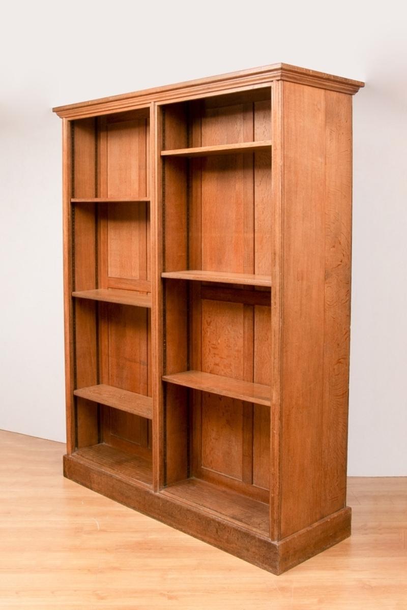 An antique open bookcase in oak, with adjustable shelves, bevelled cornice, and plinth base.