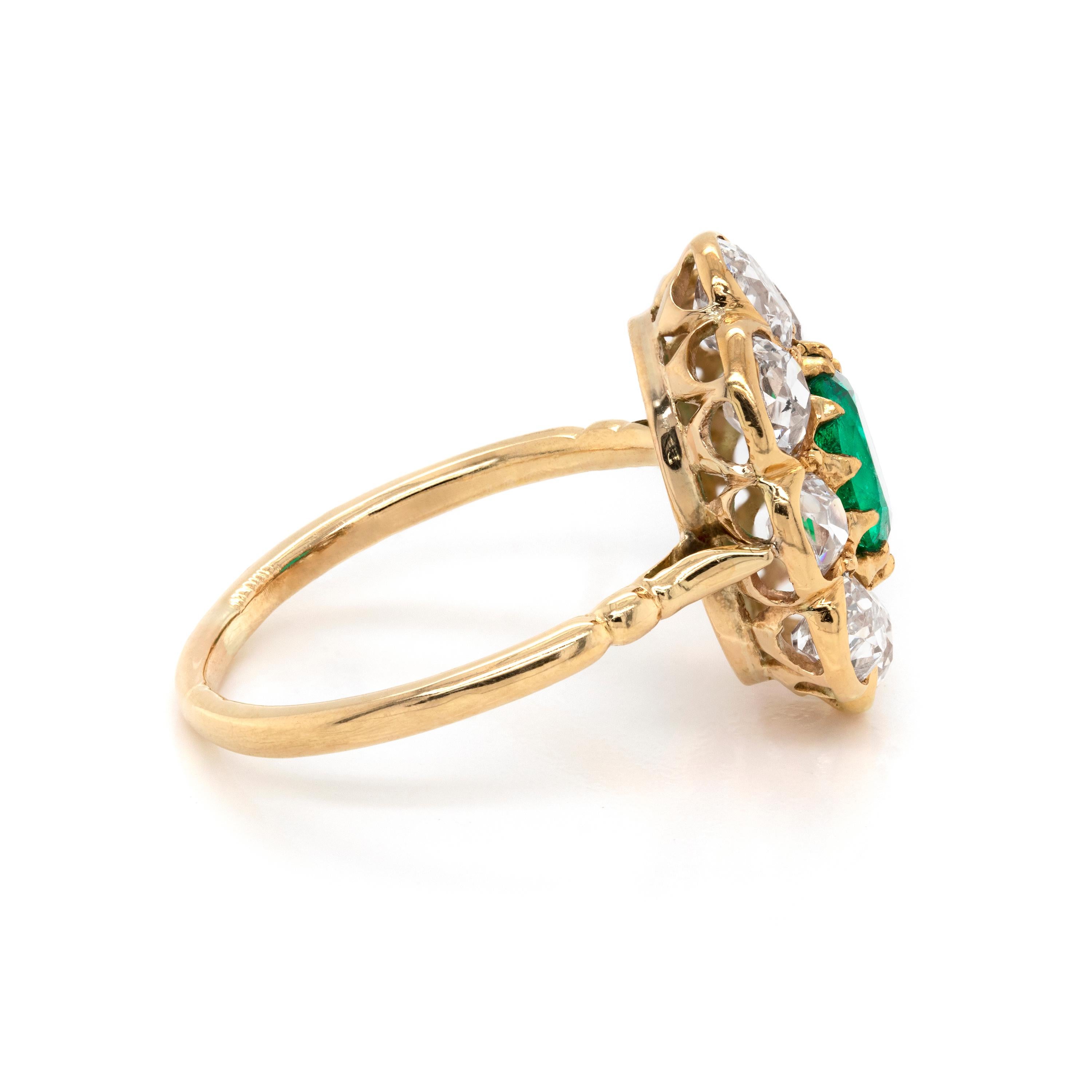 Natural emerald and diamond cluster ring featuring an oval shaped vibrant emerald in the center mounted an open back claw setting with an approximate weight of 1.00 carat. The emerald is beautifully surrounded by eight old cut diamonds in open back