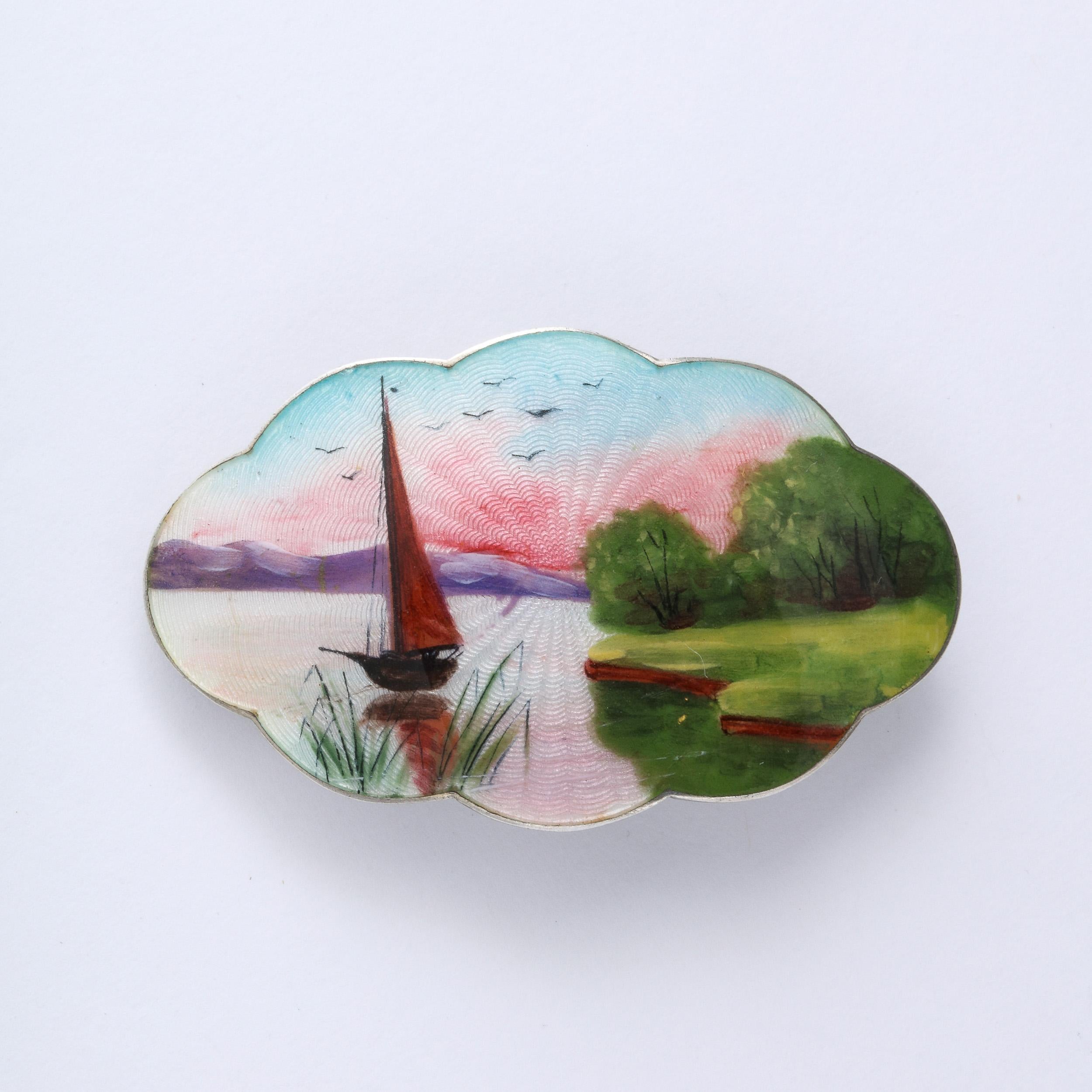 This exquisite brooch features a stylized cloud from design embellished with an exquisite landscape pictorial executed in hand done Guilloche enamel . The scene is one of a twilight seascape in rich colors. A unusual and rare piece to add to your