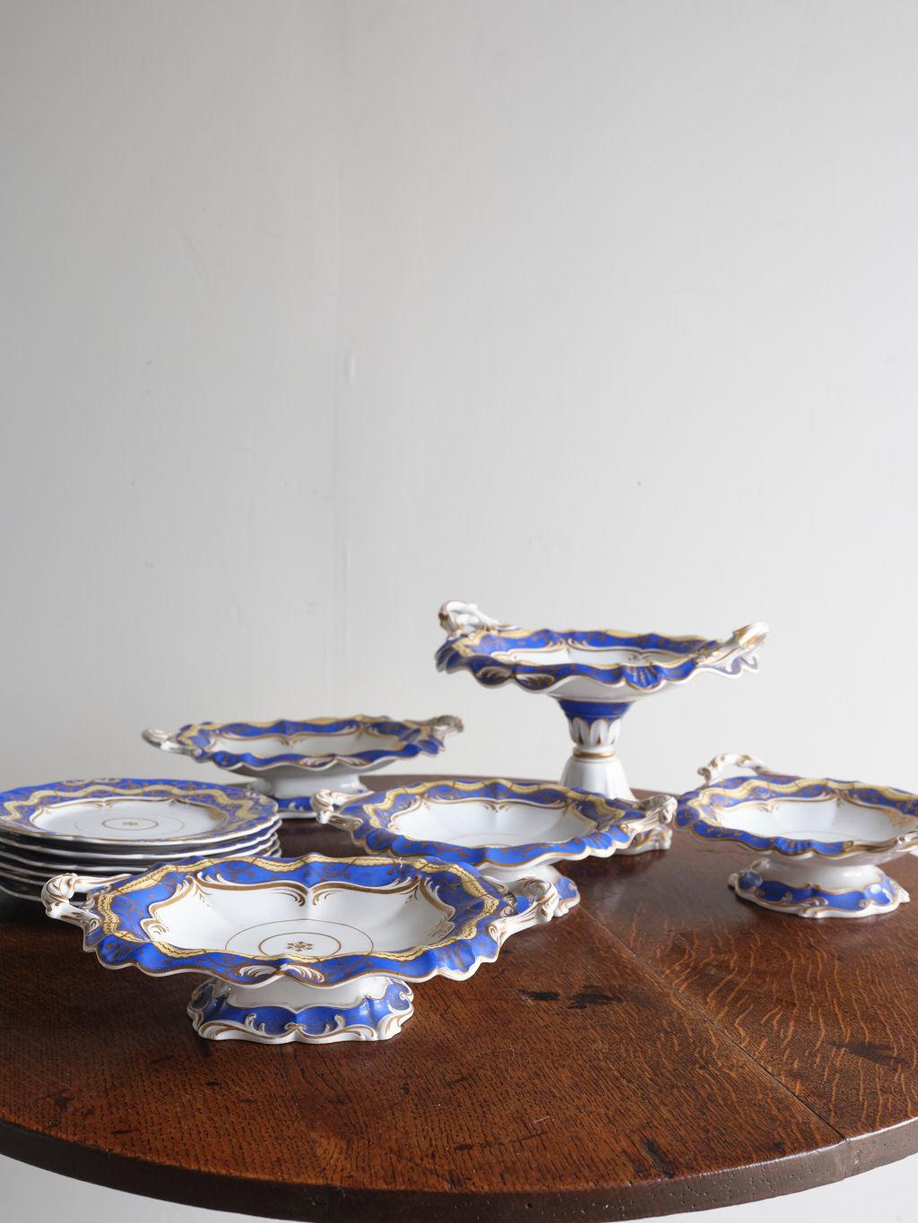 This late Victorian English Dessert service set, circa 1880, would make a lovely addition to your dining room for a dinner party. Beautifully potted and hand painted, this set features luxurious blue, white, and gold coloration. This dessert set