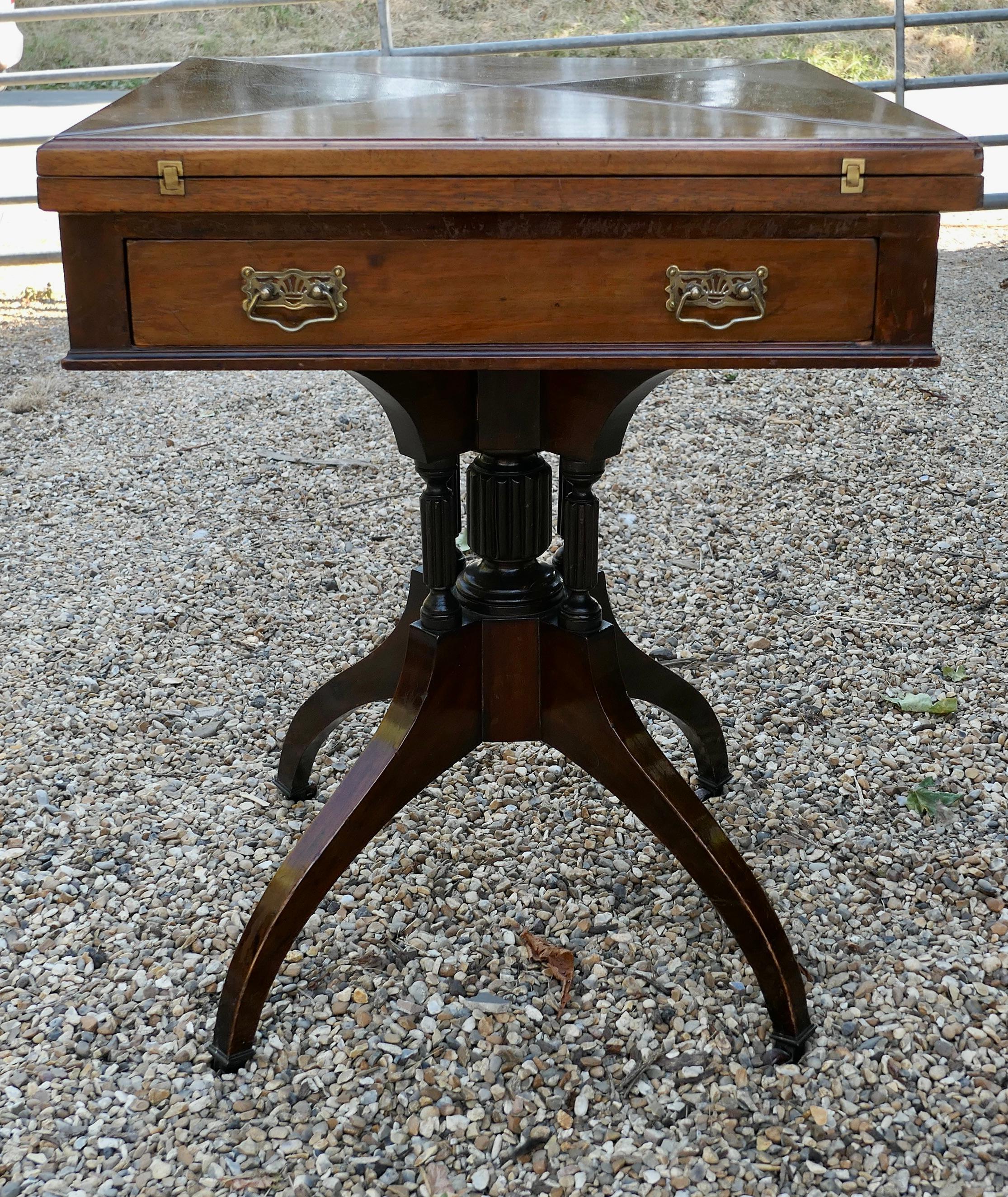 Late Victorian envelope card table with gaming wells.

A beautifully designed piece, the sturdy 4 footed leg supports the 4 triangular hinged leaves which swivel and open out to reveal a good size card table with gaming wells and a recovered baize