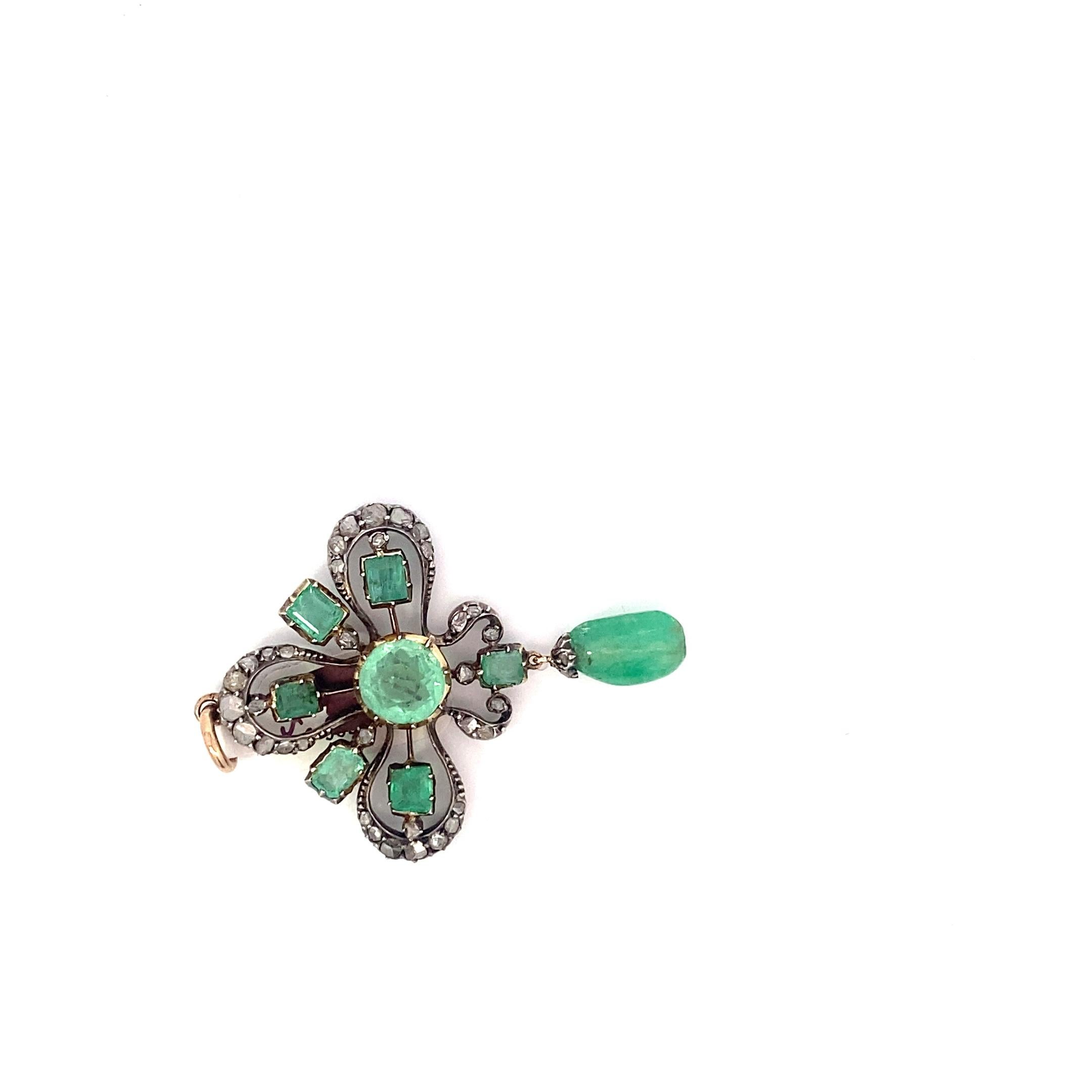 Incredible luscious Emerald forward pendant. This piece dates back to the late victorian period and features a large round emerald at the center surrounded by 6 smaller square emeralds as well as a border of rose cut diamonds between 2 and 4mms. The
