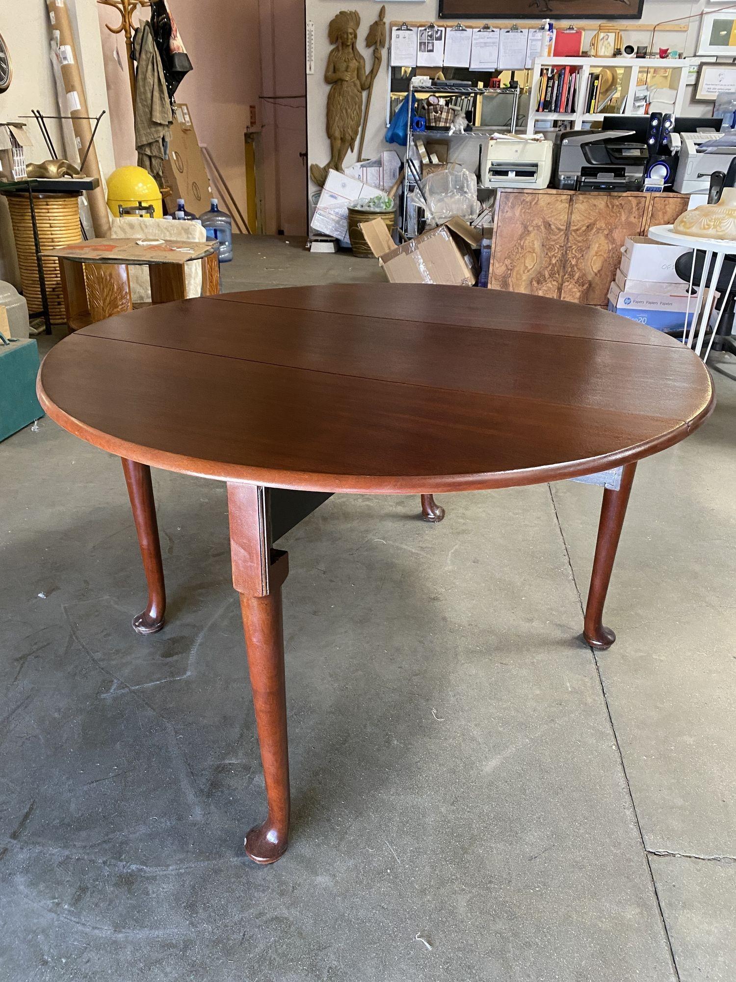 Early 20th-century French drop-leaf dining table crafted from solid Oak hardwood. The top sits over a simple apron supported with four wonderfully turned legs. Each drop leaf has a wood support that pulls out with a wood handle from under the table.