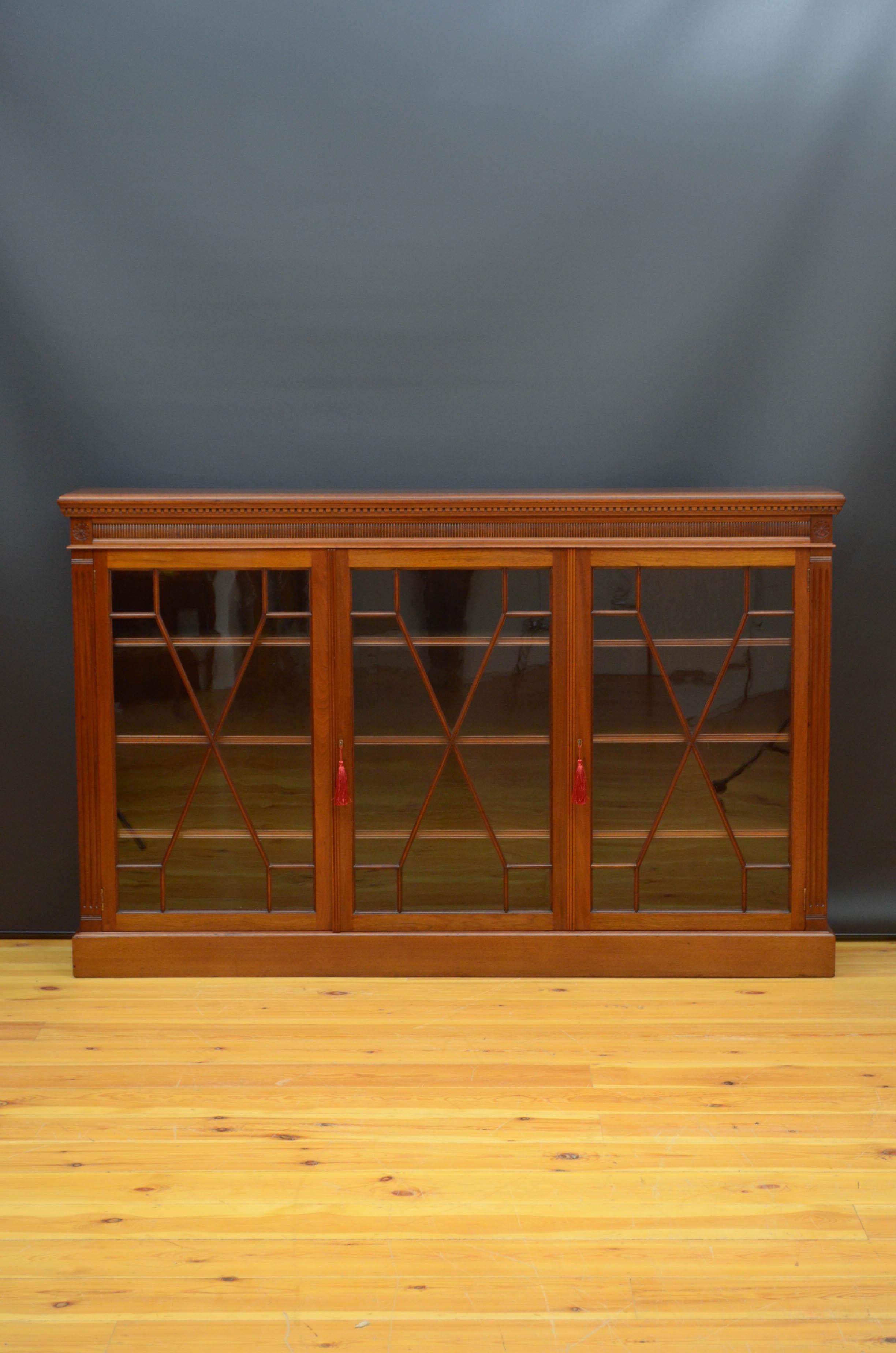 Sn5044 large late Victorian bookcase in walnut, having oblong top with moulded edge and dentil carving above convex reeded frieze and three astragal glazed doors, fitted with original working locks and keys and enclosing height adjustable shelves,