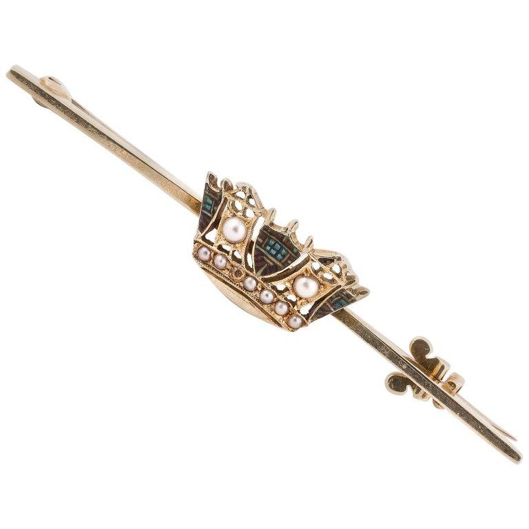 

A Victorian 18kt gold dress pin decorated with an enamel and micro seed pearls crest crown, overall length 51 mm.