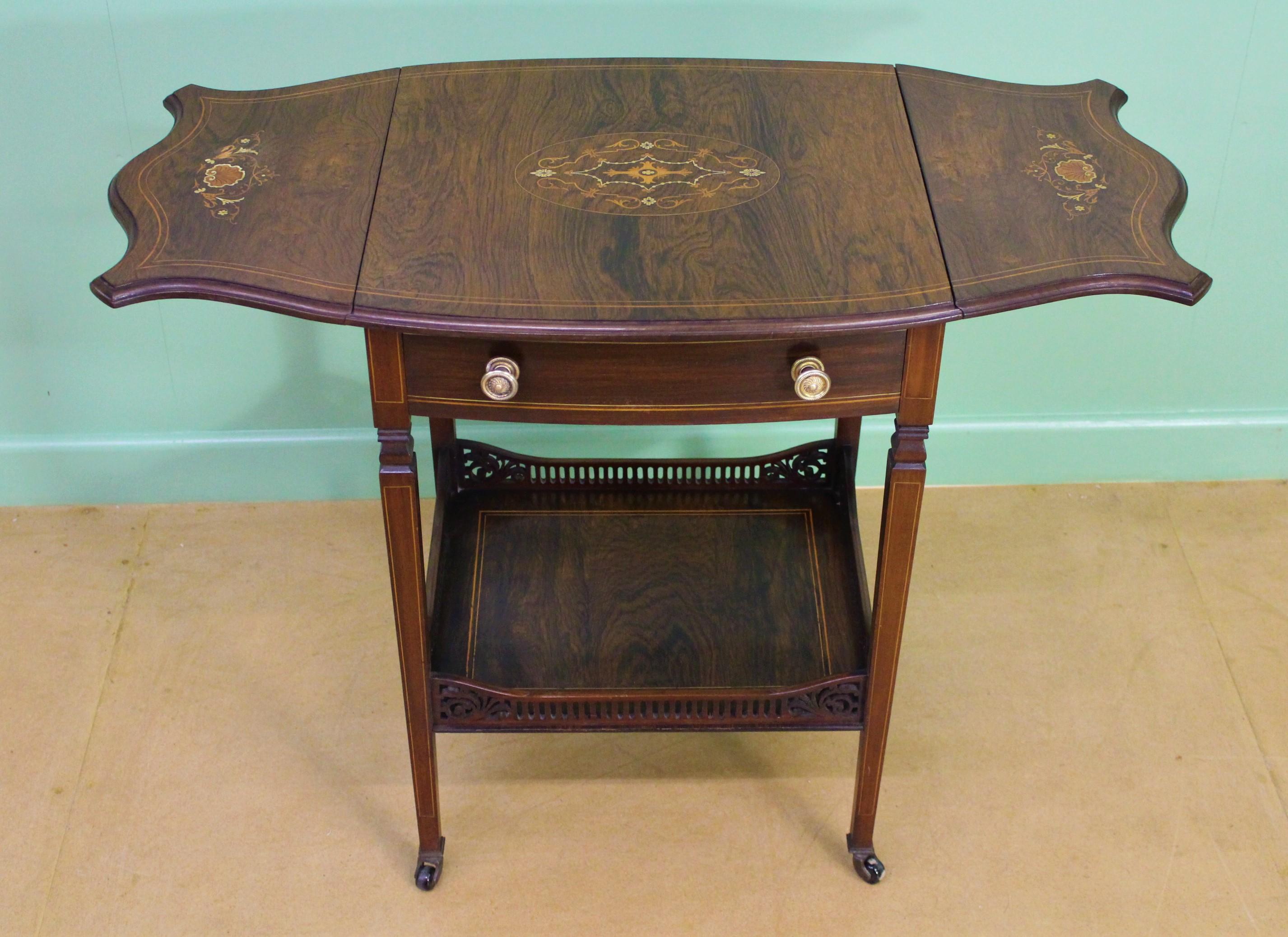 An excellent late Victorian period inlaid rosewood flap table. Well-constructed in solid mahogany with attractive rosewood veneers. Decorated with inlaid stringing throughout and floral panels to the top and each of the flaps. With a single drawer