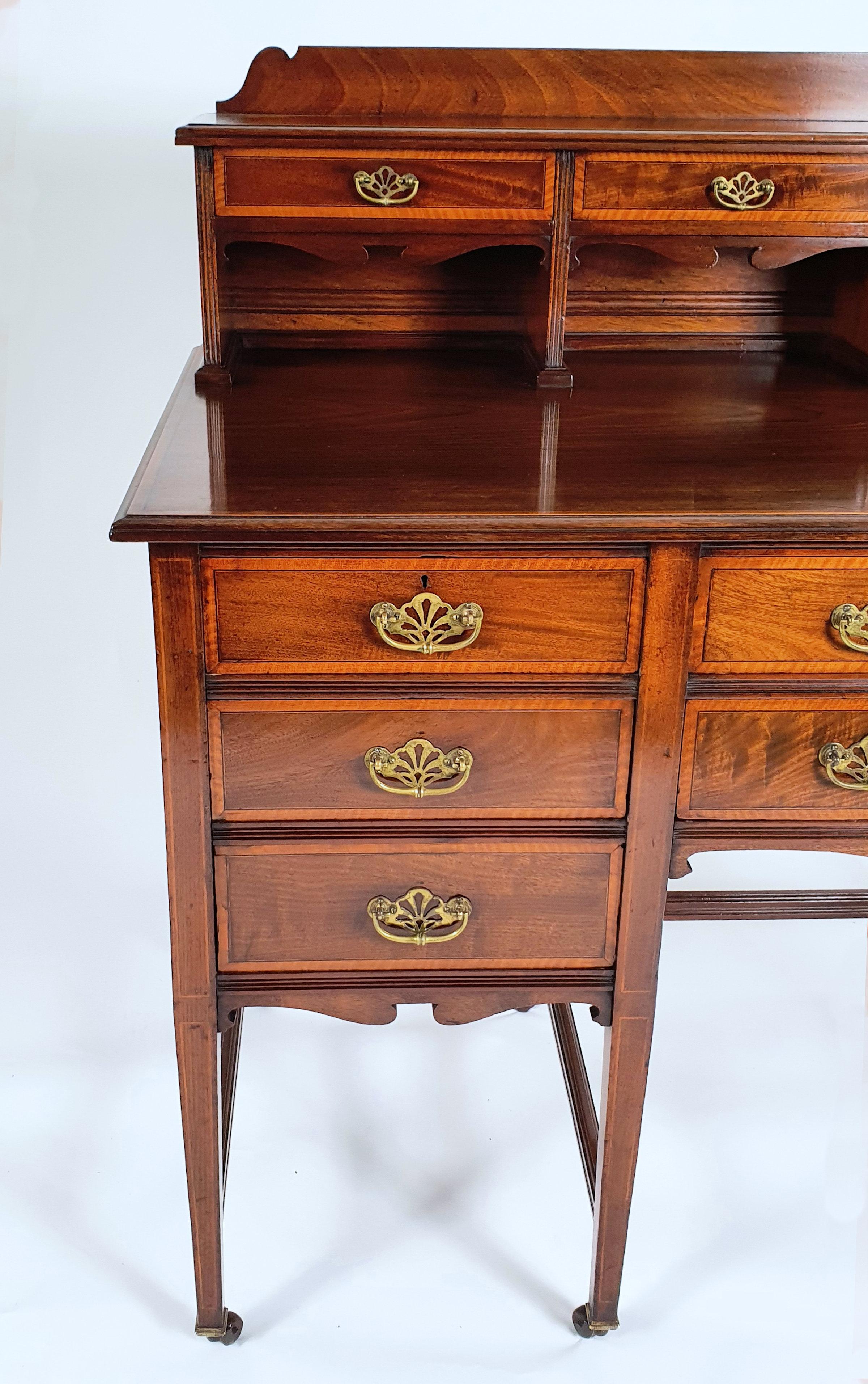 This late Victorian inlaid walnut side cabinet features 3 small drawers over pigeon holes along the top with 3 small drawers and 2 long drawers below. The cabinet is supported over a stretchered base with the original pierced brass handles. It