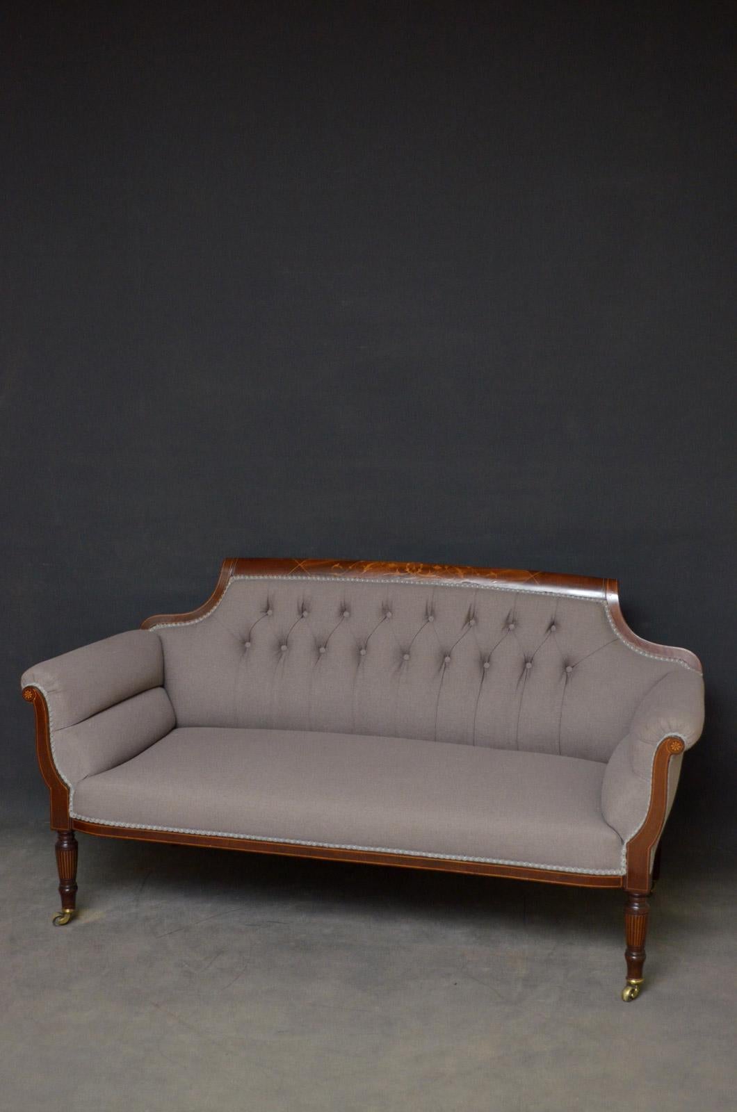 Sn4542 fine quality late Victorian mahogany settee, having flora inlaid top rail, buttoned back, generous seat and inlaid arms, standing on turned and string inlaid legs terminating in original brass castors. This antique sofa retains its original