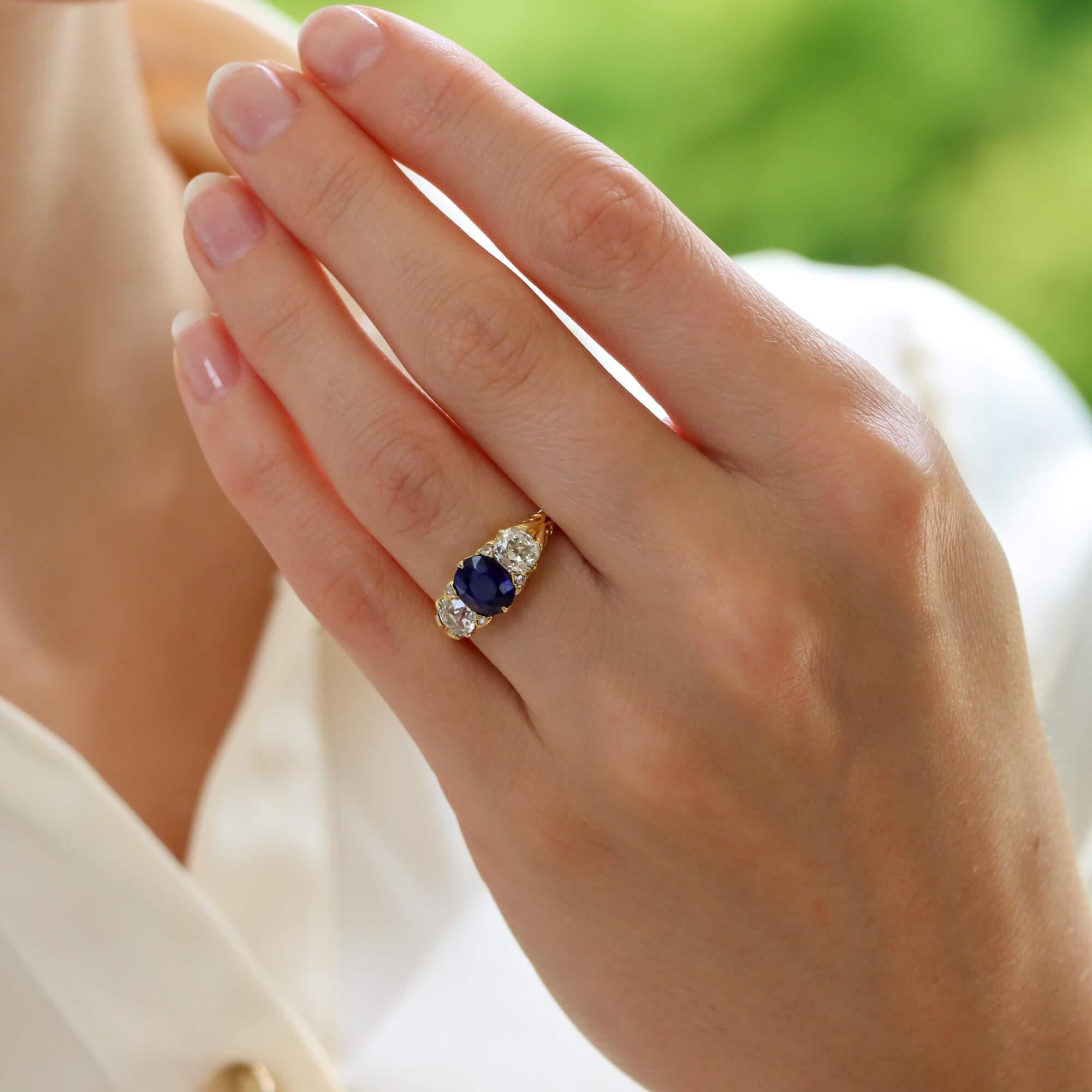  A beautiful late Victorian old mine cut diamond and sapphire three stone ring set in 18k yellow gold.

The ring is centrally set with a stunning 1.65-carat old cut vibrant blue sapphire. To either side of this central stone are two perfectly