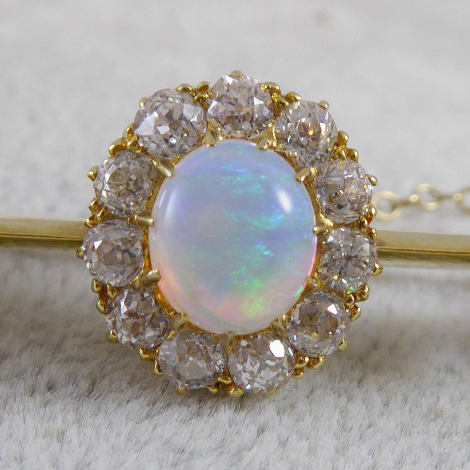 A stunning opal and diamond bar brooch from the late Victorian era, circa 1890s.  Set to the centre of a knife edge gold bar a cabochon cut opal with a border of old cut diamonds. This opal and diamond cluster measures approx. 12.00mm x 10.00mm. To