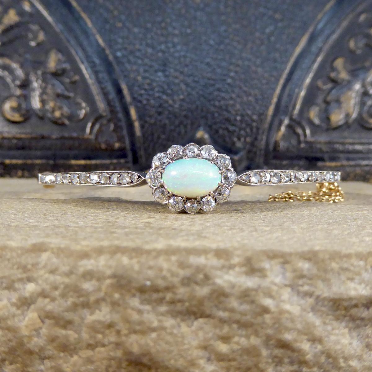 This beautiful antique bracelet was hand crafted in the Late Victorian era from 14ct Yellow gold with a Silver top for the settings. This gorgeous example of a Late Victorian Bangle features an Lustrous Opal with a surround of Old Cut Diamonds