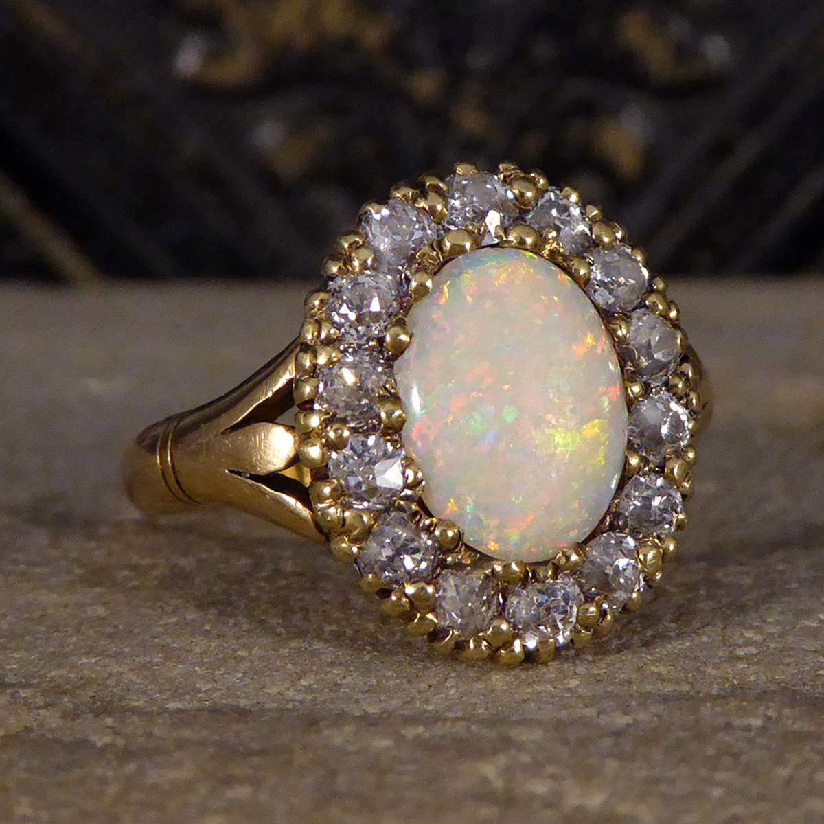 A classic antique cluster ring hand crafted with great care in the Late Victorian era. Featuring in this ring is bright and colourful oval shaped Opal. The Opal projects a reds and oranges with flashes of green and blue as the light hits the stone