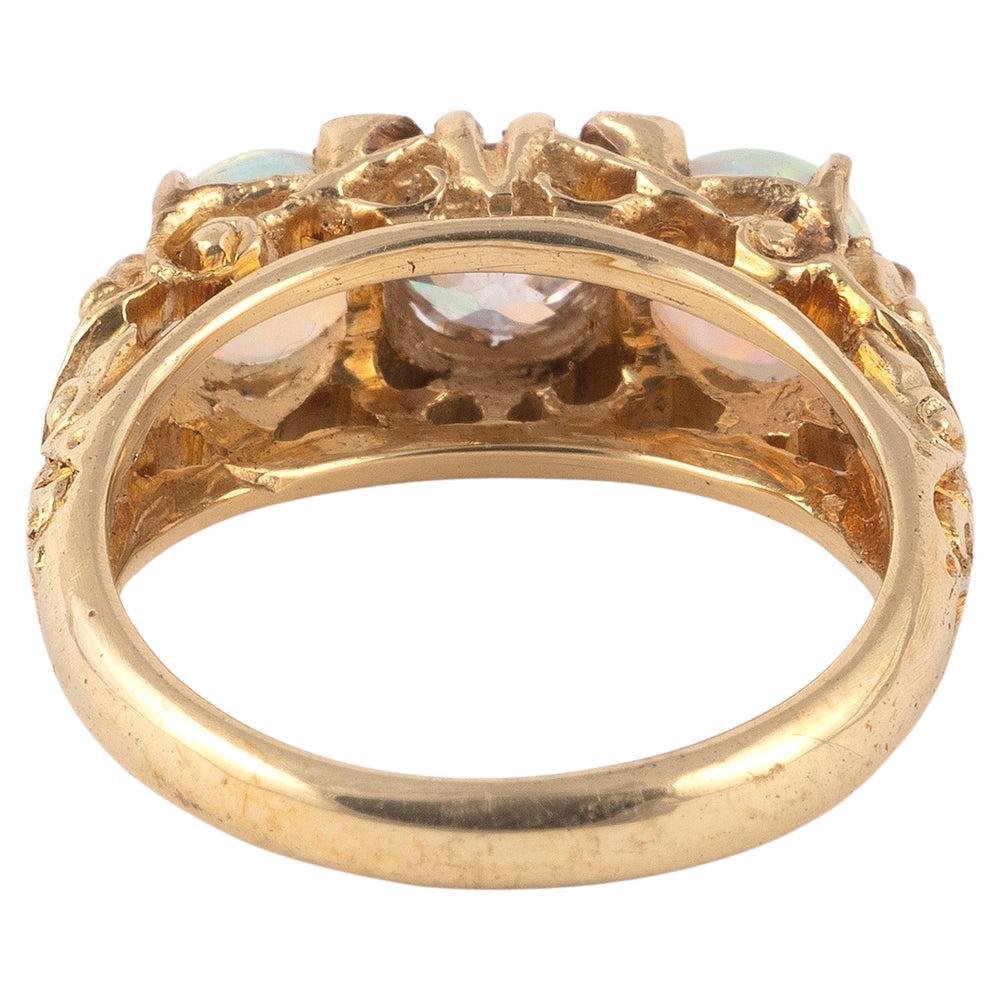 Un anello antico a tre pietre dallo stile impeccabile risalente alla fine dell'epoca vittoriana, circa 1890. È incastonato da due vibranti opali, con un diamante taglio vecchia miniera tra l'uno e l'altro. Gli opali sono ben graduati, con lampi di