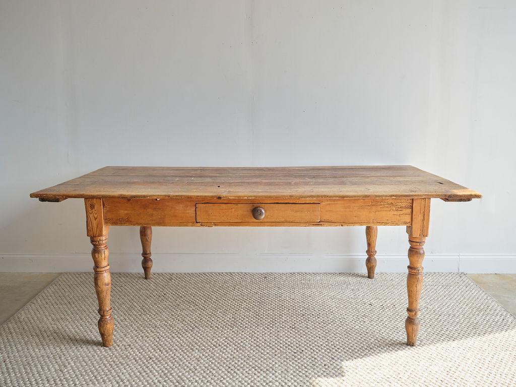 This late Victorian farmhouse dining table would make a lovely addition to any dining room. The finish is polished, and it has one single drawer. The four legs have unique curves and indentions. This table is simple and functional and has a solid
