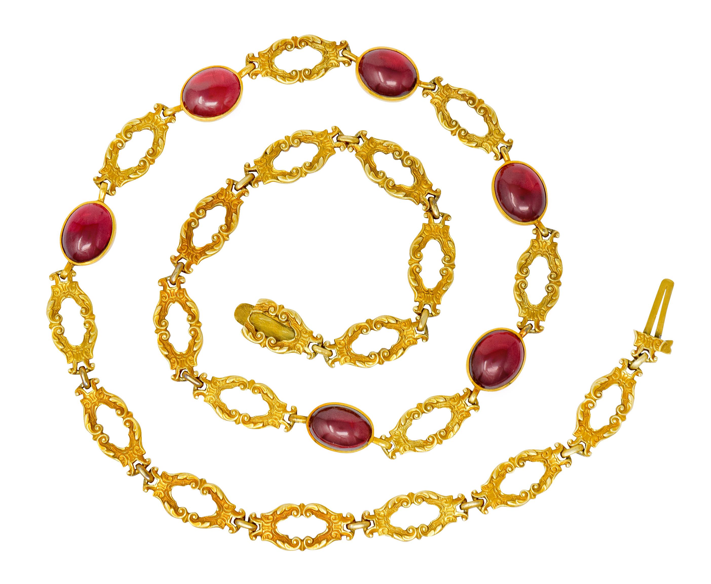 Collar style necklace is comprised of scrolled foliate whiplash links with deeply engraved details

Bezel set to front with six oval rhodolite garnet cabochons measuring approximately 10.5 x 9.0 mm

Very well-matched and transparent with strongly