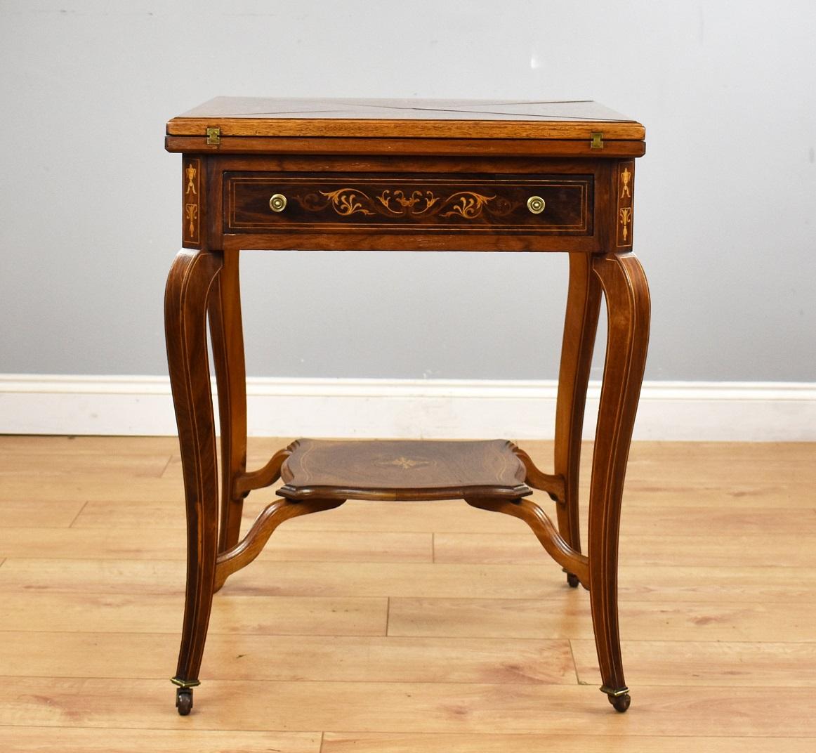 Victorian rosewood envelope card table in good condition having been polished by hand. The top has decorative inlay and swivels to open each section to reveal a green base with holders for counters or coins etc. below this it has a draw with inlay