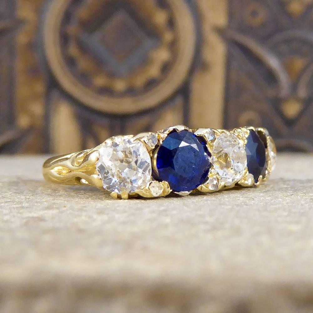 Such a lovely antique ring hand crafted in the Late Victorian era with a beautifully detailed 18ct Yellow Gold gallery and carved shoulders. Holding three sparkling Diamonds weighing a total of 1.04ct  and two dazzling deep blue Sapphires weighing