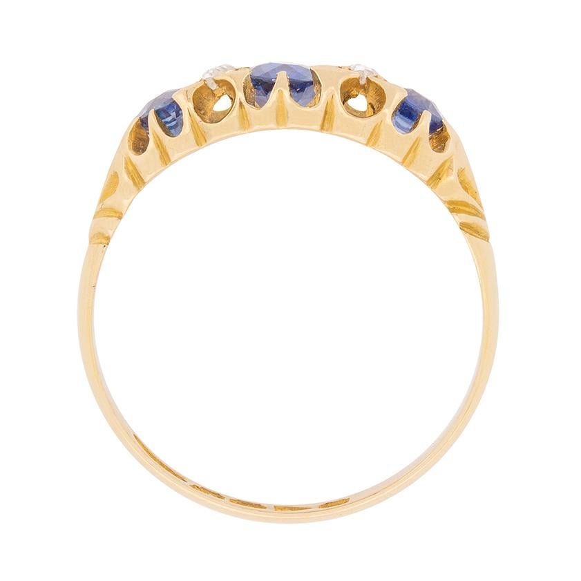 Dieser originelle Ring aus der viktorianischen Epoche zeigt drei ovale Saphire, die mit vertikal gefassten Paaren von Diamanten im Rosenschliff besetzt sind, und ist aus 18 Karat Gelbgold gefertigt.

Die Fassung des Rings stammt aus den frühen