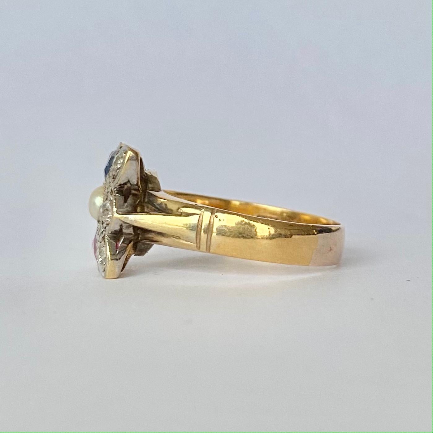 Dieser wunderschöne Ring enthält einen leuchtend blauen Saphir und einen roten Rubin, die beide jeweils 30 pt messen. Auf beiden Seiten dieser Steine sitzen Diamanten. In der Mitte befindet sich eine Perle. Die Diamanten ergeben insgesamt 30 Punkte.