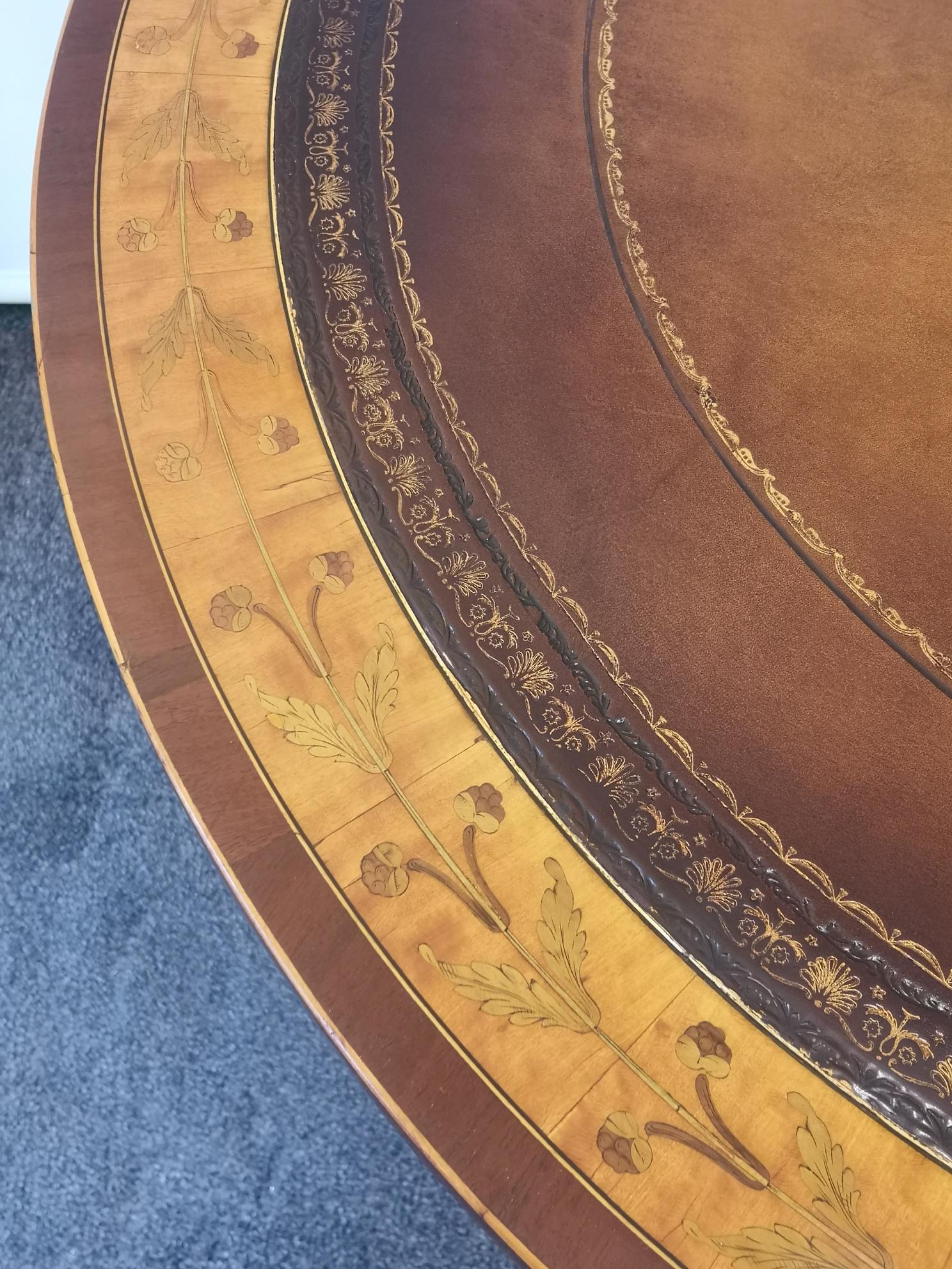 Late 19th century Satinwood circular drum table, the revolving top with a brown tooled leather and marquetry, above 4 real and 4 false drawers. On a mahogany four legged base and brass castors.
English, circa 1890.
 