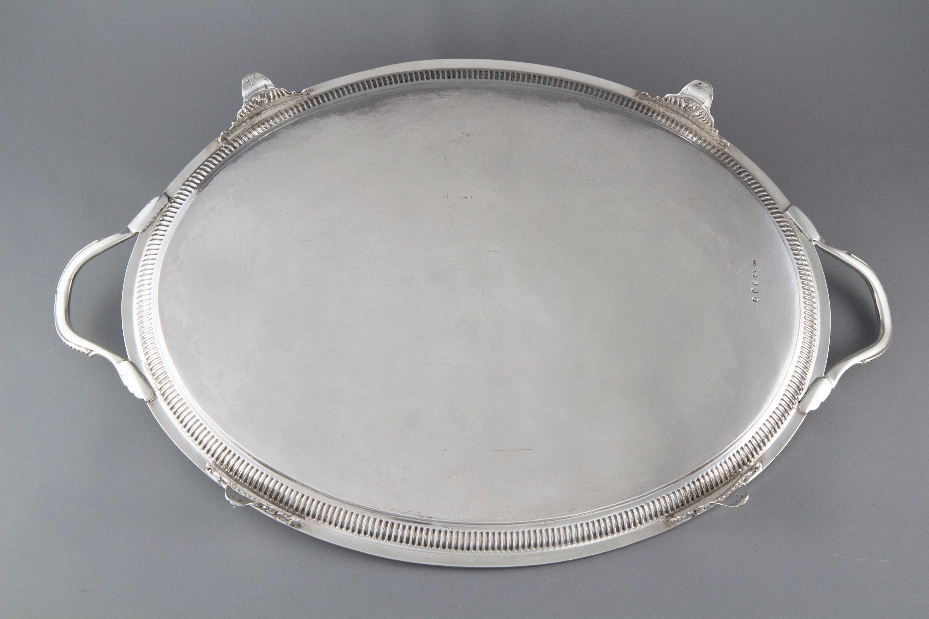 A good quality two handled silver tray of oval form. The edges with gadroon and bead decoration. The central plate engraved with bright cut foliate and floral arabesques surrounding a vacant oval cartouche. The reeded handles with bead and feather