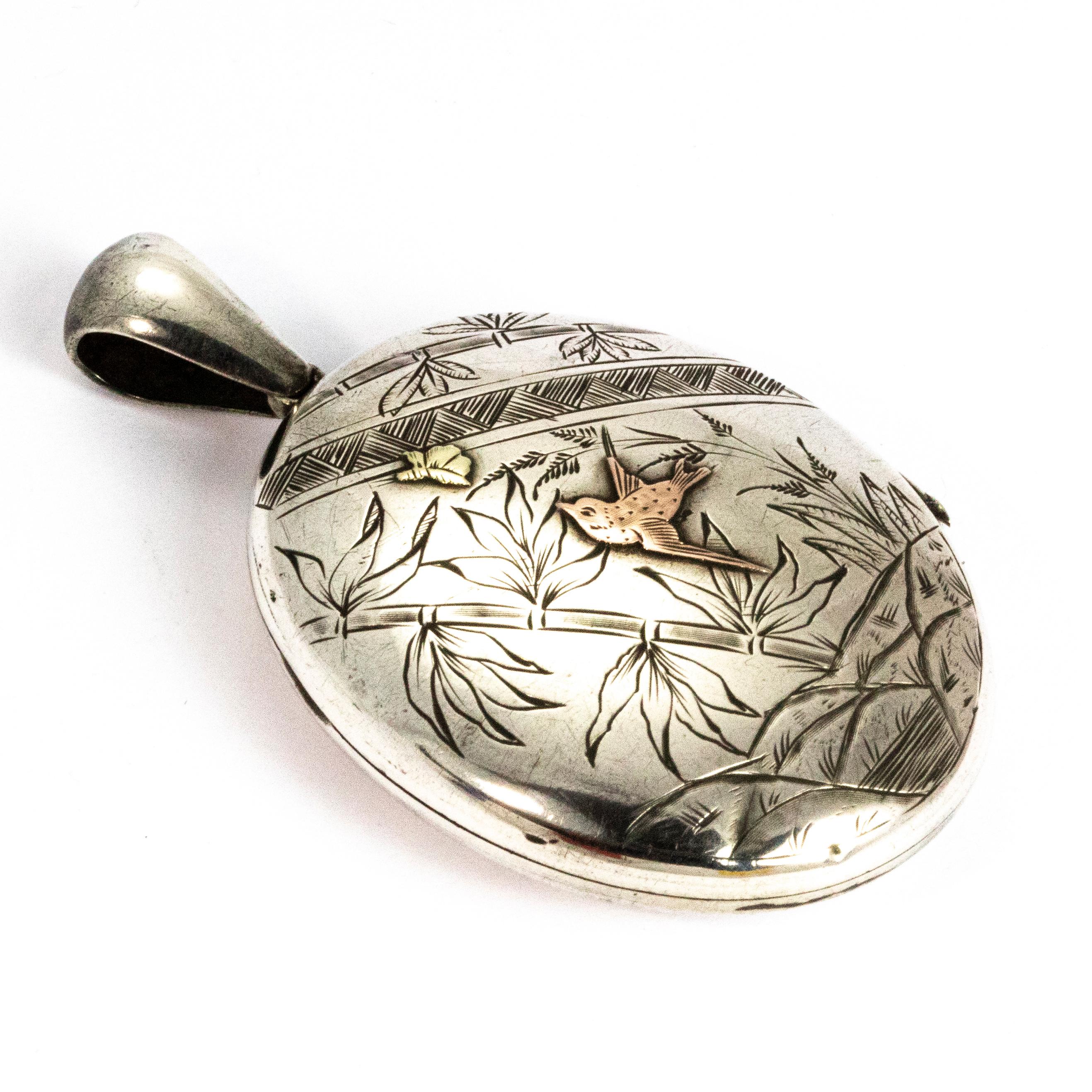 This wonderful late victorian locket is modelled out of silver but features a delicate rose gold bird and yellow gold butterfly. The silver locket itself is finely engraved with an out door scene that looks almost oriental themed with a bamboo style