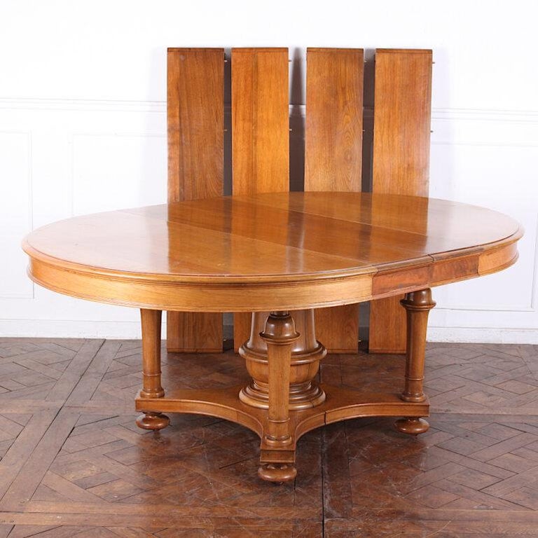 An unusually-large round dining table in solid walnut extending to take up to six original skirted matched leaves. The table is of ‘split pedestal’ design as shown in the photos. Two leaves can be inserted with the pedestal together; when extended