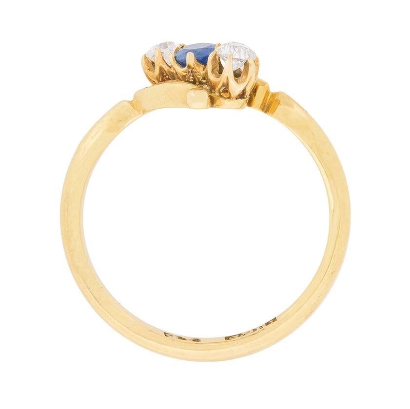 A delicate three stone twist ring, showing off a beautiful deep blue sapphire, surrounded by to diamonds. The sapphire weighs 0.15 carat, and the diamonds 0.20 carat total. They are claw set and the wonderful twist design is classic of the late