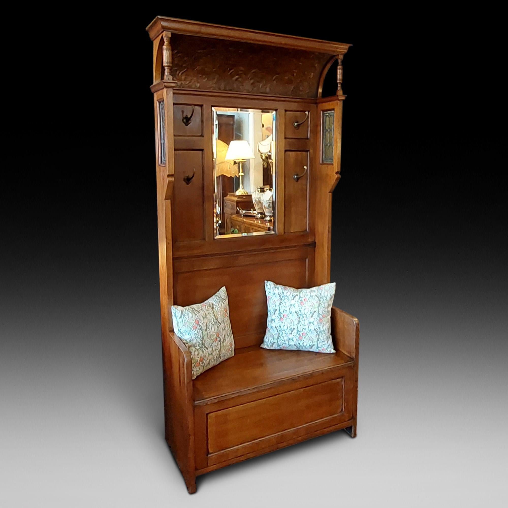 Late Victorian Walnut Hall Stand/Settle having a cavetto floral moulded canopy over a bevelled glass mirror and four brass coat hooks with leaded glass panel sides, over a box base with lift up seat 39