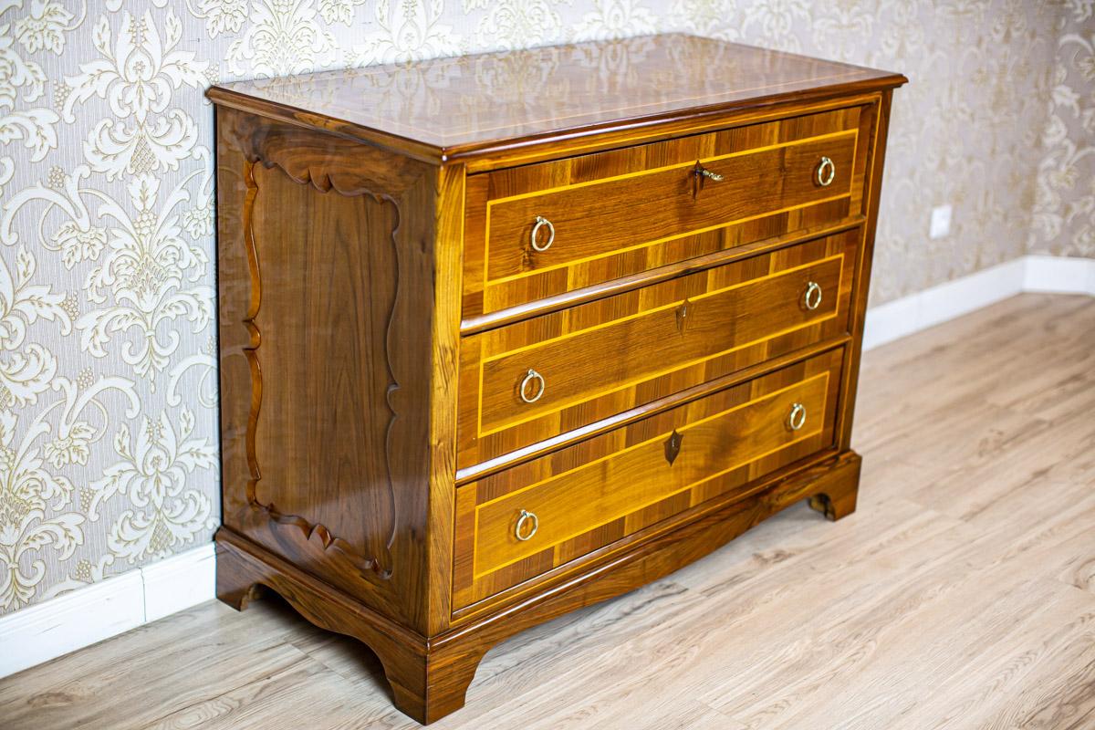 Late 19th Century Commode with Cartousche-Shaped Decorations

We present you this dresser with three drawers and a slightly advanced cornice base.
The simple form of the piece is only varied by the veneers in two shades and decorations in the form