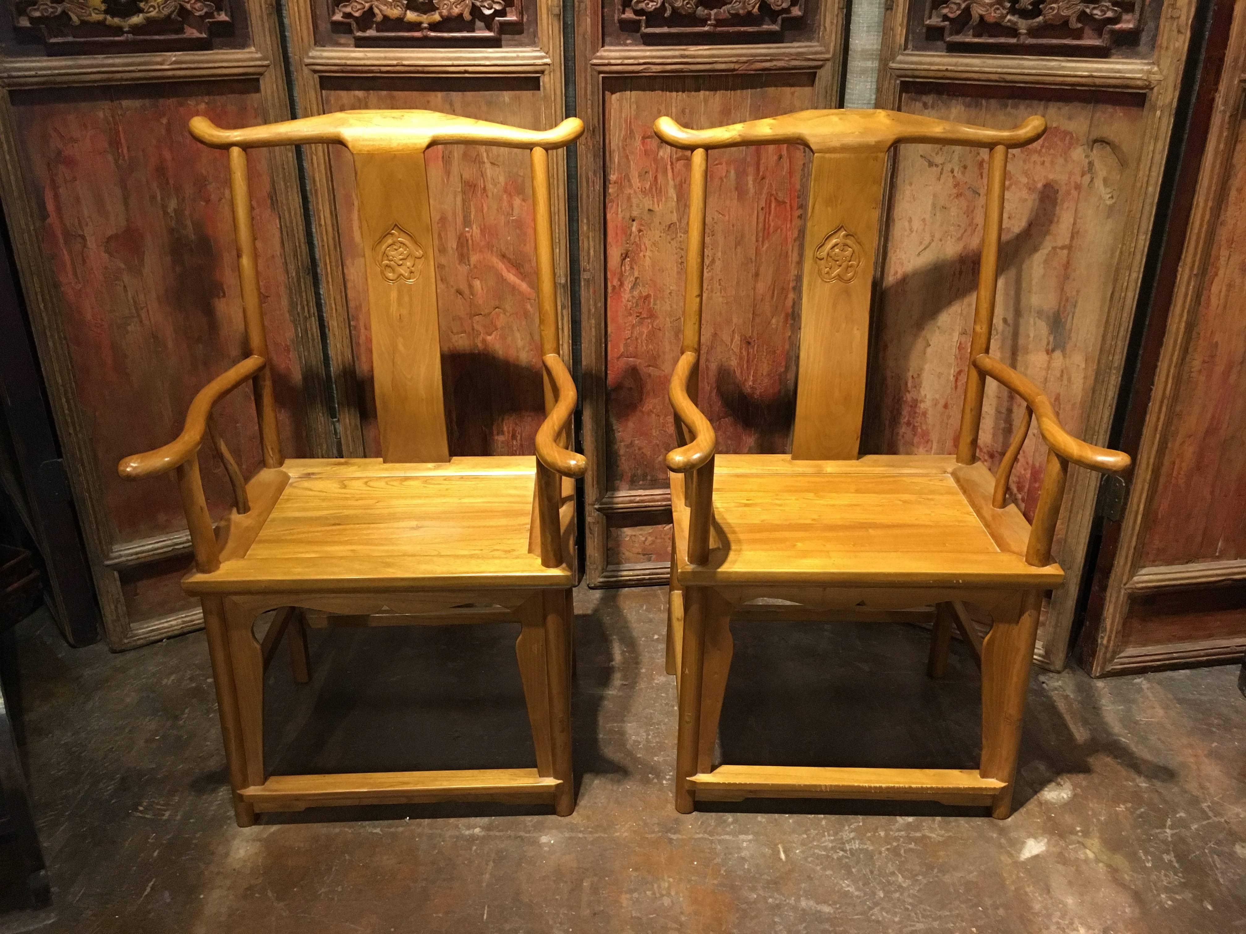 A stunning pair of 20th century Chinese yoke back armchairs crafted of cypress, baimu. 
The chairs of typical style and construction, and known as official's hat chairs or yoke back chairs, because of the shape of the crest rail. The chairs solidly