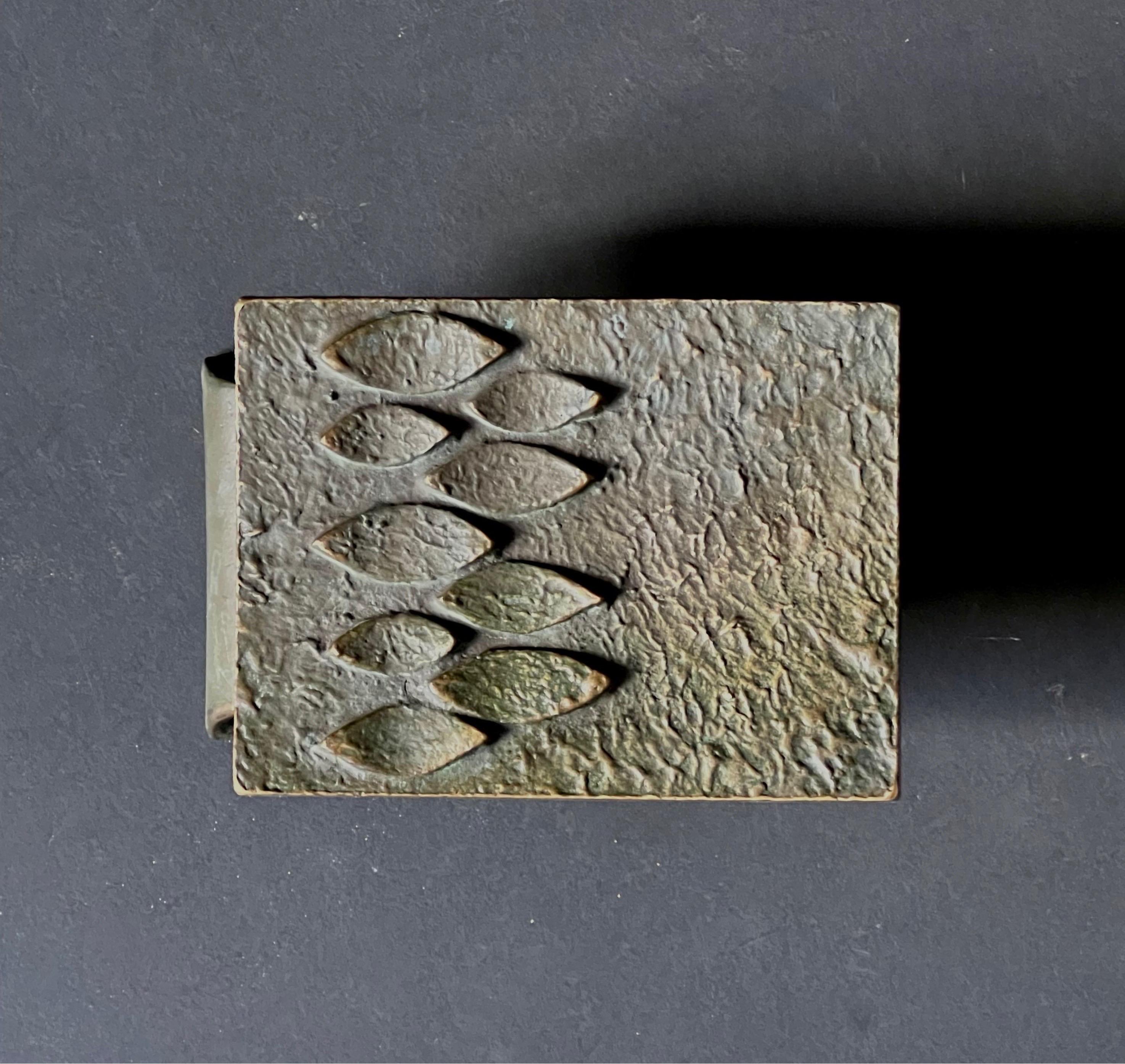 A lateral bronze push or pull door handle with an abstract organic design on a concave plate. Mid-late 20th century, European.

The handle is in good vintage condition, and the metal has a dark patina, with oxidation and signs of wear in line with