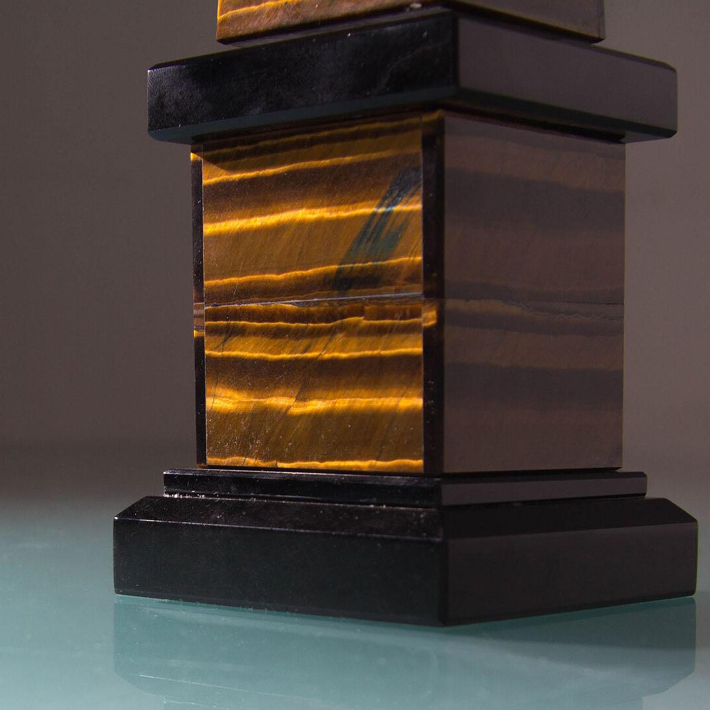 Ispirata all'antico obelisco di origine egizia che si trova a Roma e che ha un gemello a Istanbul, in Turchia, questa scultura a forma di obelisco sfoggia il calore e il fascino del pregiato occhio di tigre e dell'ossidiana nera. L'uso di pietre