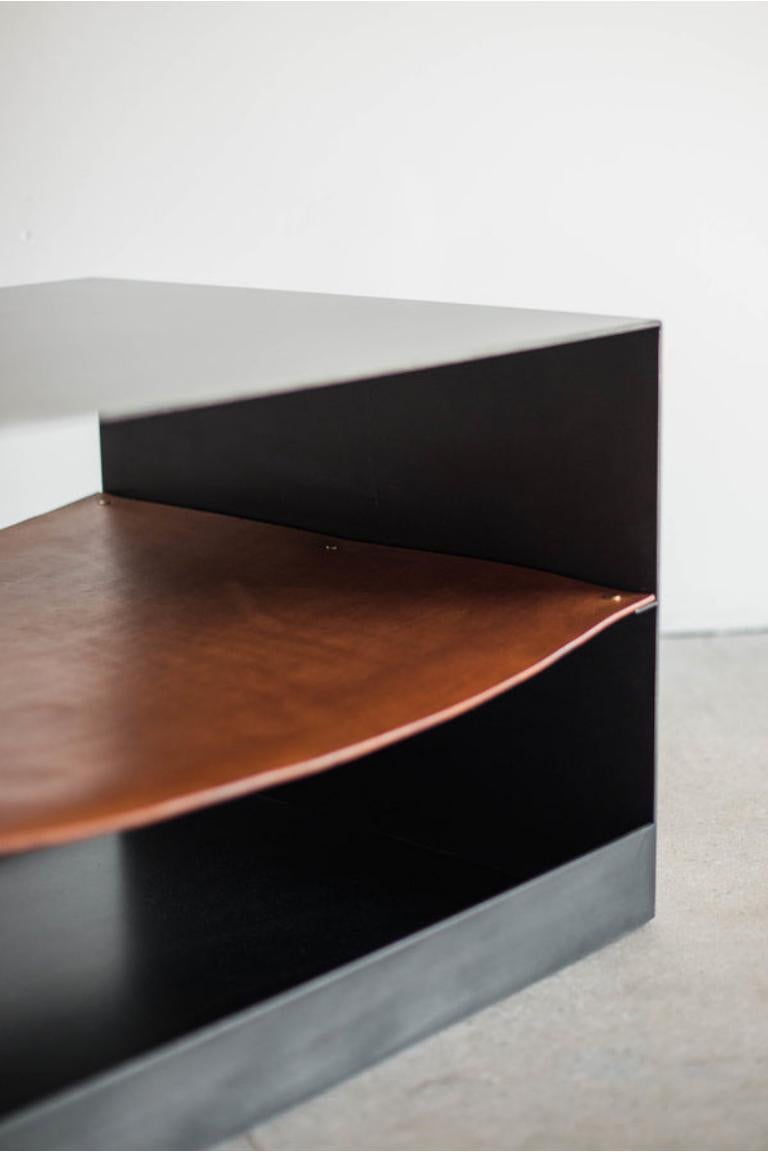 La table d'appoint Latigo incarne l'essence de la série Latigo avec son corps en acier industriel et ses marques naturelles, mettant en valeur le caractère unique du design artisanal. La large surface du boîtier est adoucie par une seule étagère en