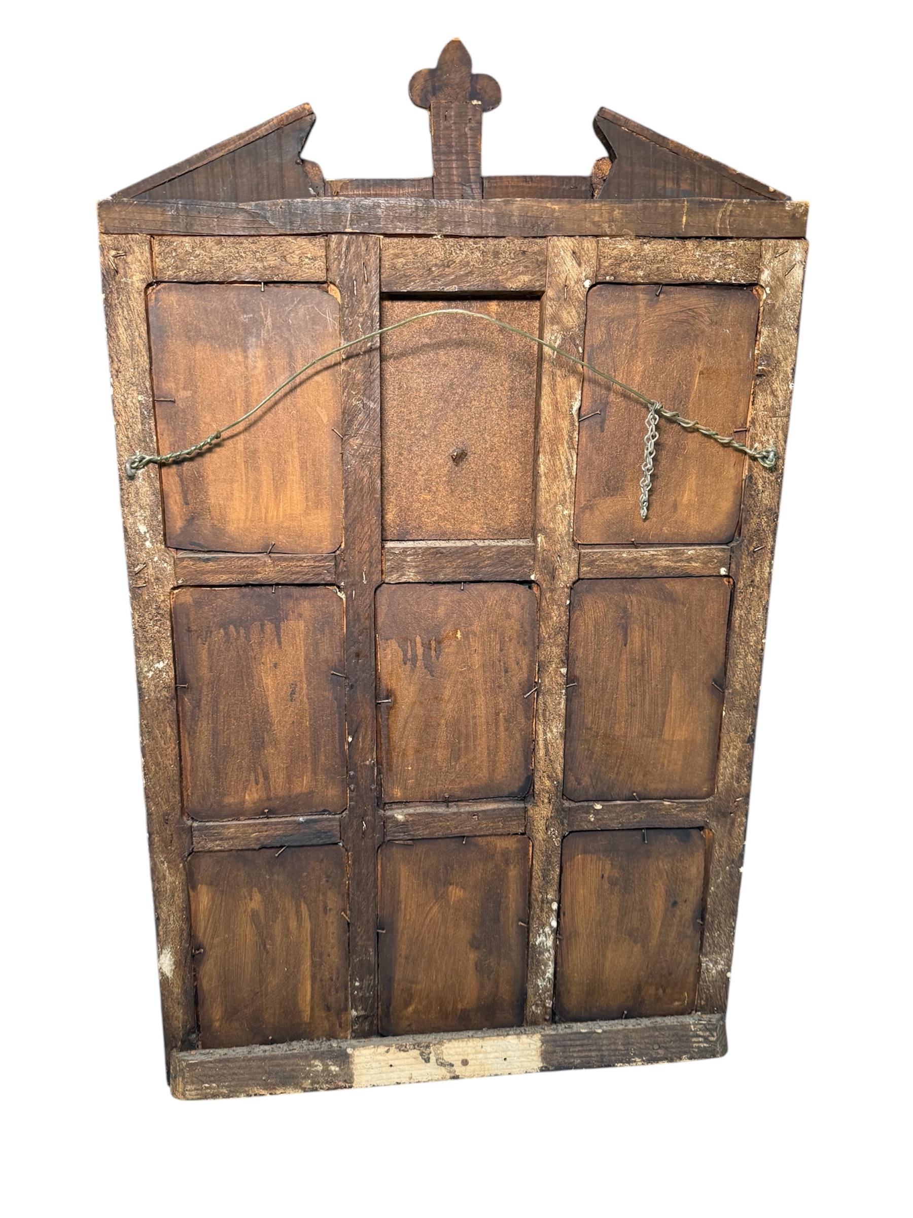 This is a Latin American Religious Folk Art Nicho Retablos Shrine. It depicts a rectangular wooden panel shaped as a neoclassical temple, but the center of the pediment is cut to accommodate a large crucifix. An octaptych will divide the portico of