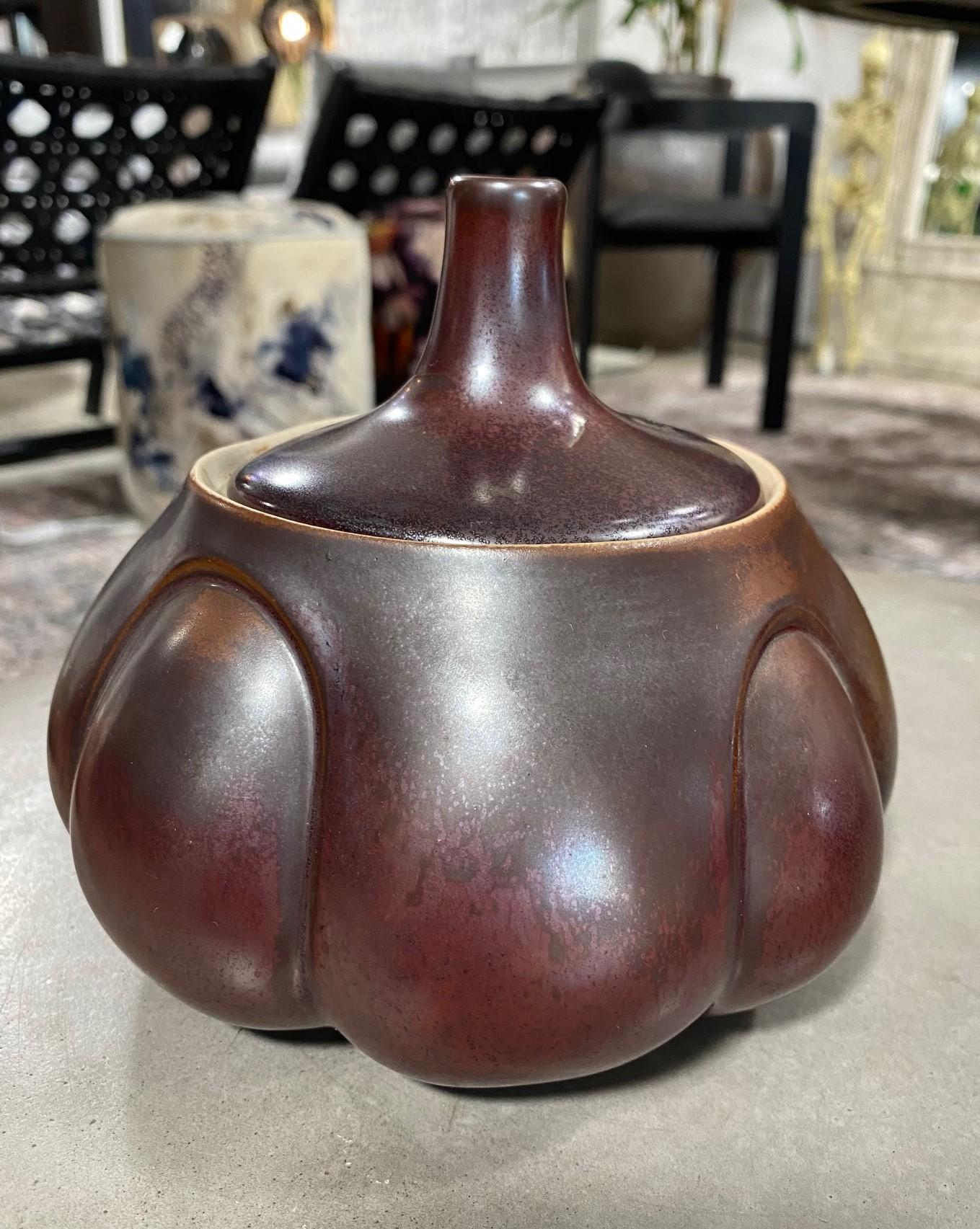 A very unusual, quite unique and presumably quite rare work by American master ceramicist Laura Andreson. This covered vessel/jar features a rounded and very voluptuous shape and a dark, rich luster (lustre) glaze. 

It is signed on the underside