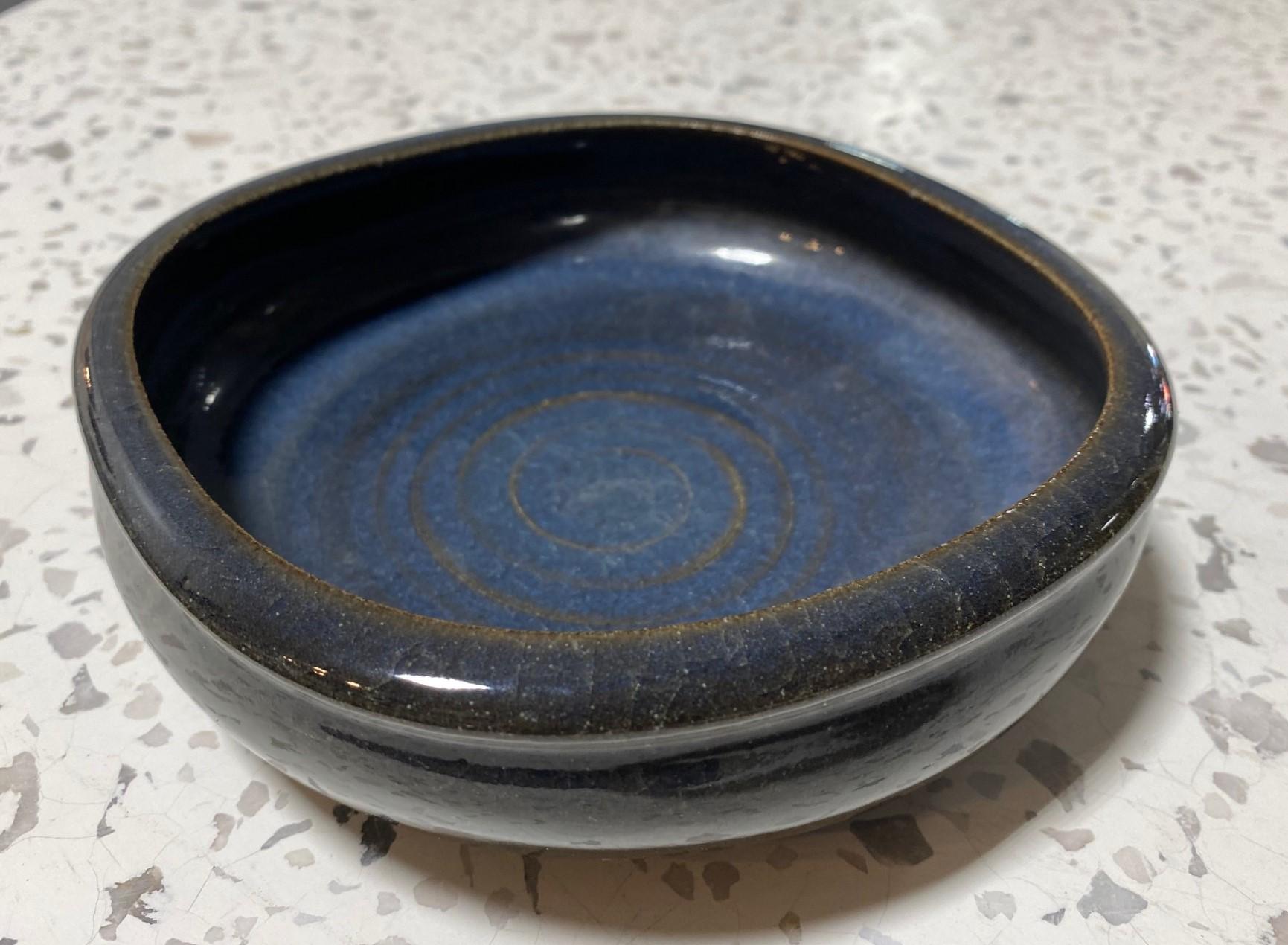 A wonderfully crafted and beautifully glazed bowl by renowned American California master potter Laura Andreson. An uncommon form for Andreson with a high gloss glaze featuring a dark ocean deep blue / aqua color with delicate splashes of greens.