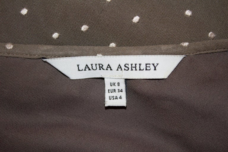 A pretty and easy to wear tea dress by Laura Ashley . In a coffee colour with white spots this silk dress, has cap sleaves, tie detail and a nice shape. It is fully lined. 
Measurements: Bust 32'', length 48''
