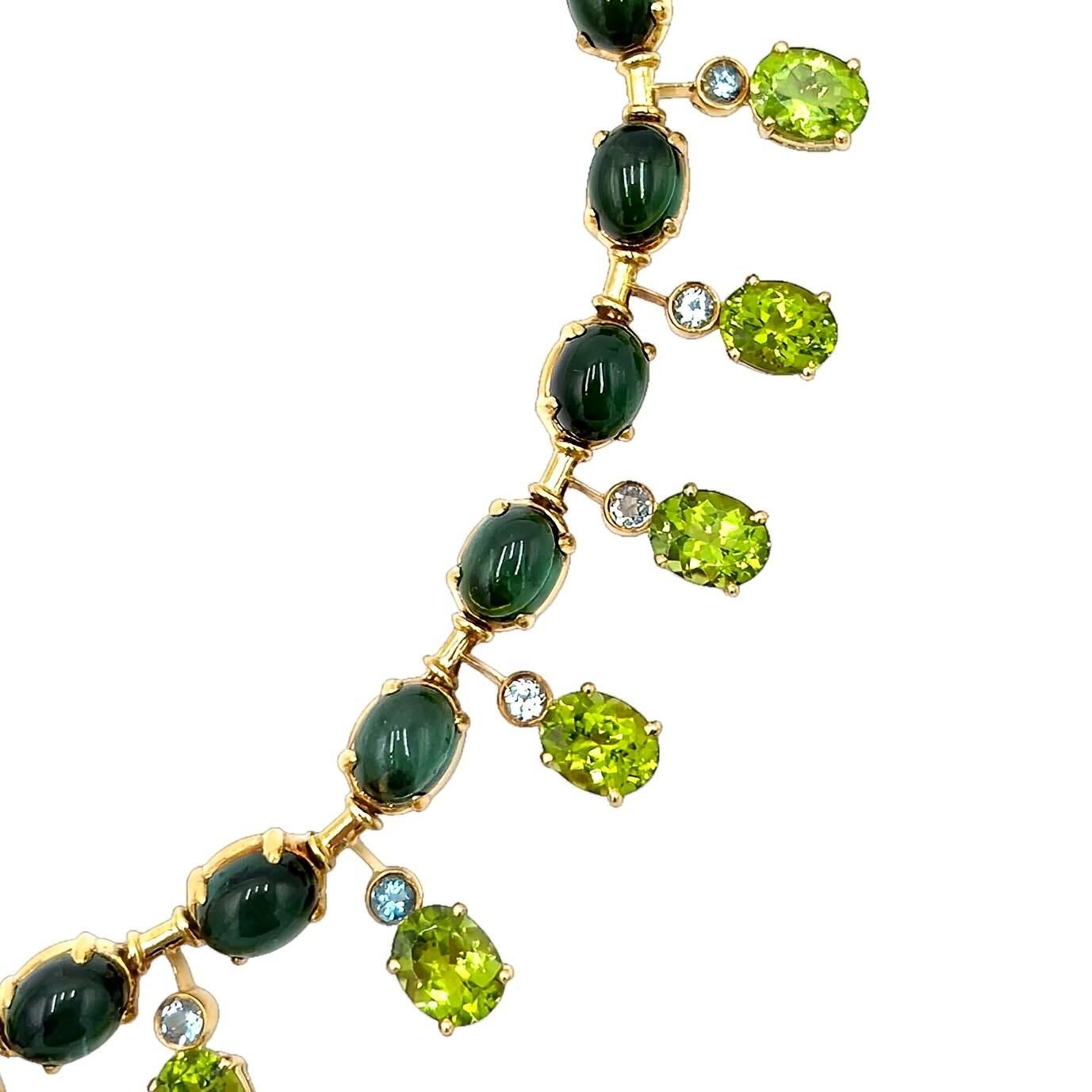 Una collana in oro giallo 18 carati, tormalina verde, peridoto e topazio blu.  Disegnata come una lunghezza di tormaline verdi ovali cabochon collegate da maglie a barretta, nella parte anteriore della collana le maglie a barretta sospendono