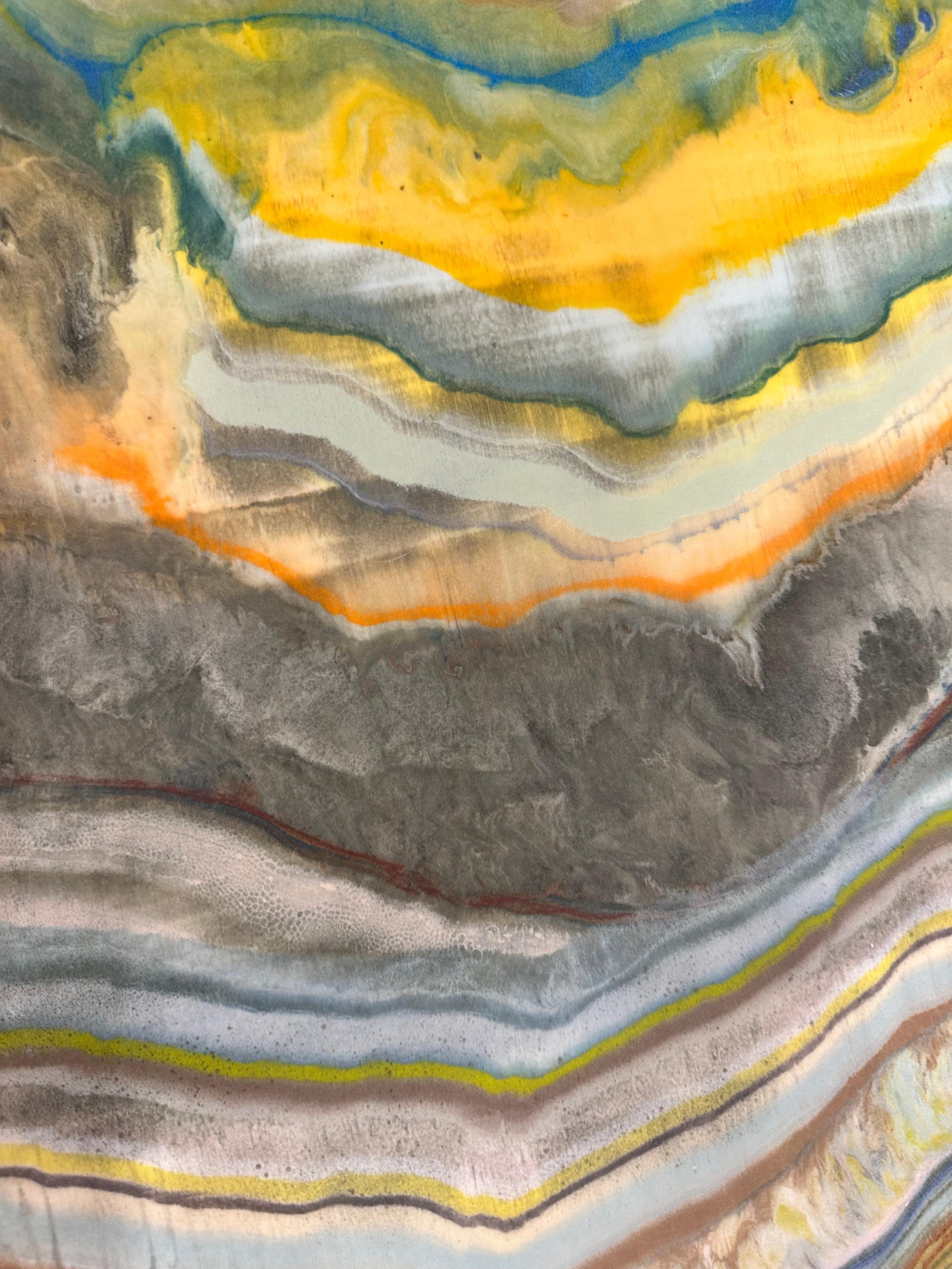 In this contemporary encaustic monotype, layers of pigmented beeswax on lightweight paper create an undulating composition suggesting layers of the earth's crust and geological formations in golden yellow, navy blue, brown, beige and yellow ochre