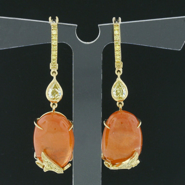 These gorgeous Laura Munder earrings are crafted in solid 18k yellow gold and carry fancy yellow diamonds and fine mandarin garnets in a beautiful drop/dangle style. The oval cabochon cut mandarin garnets show an attractive size, displaying a pure