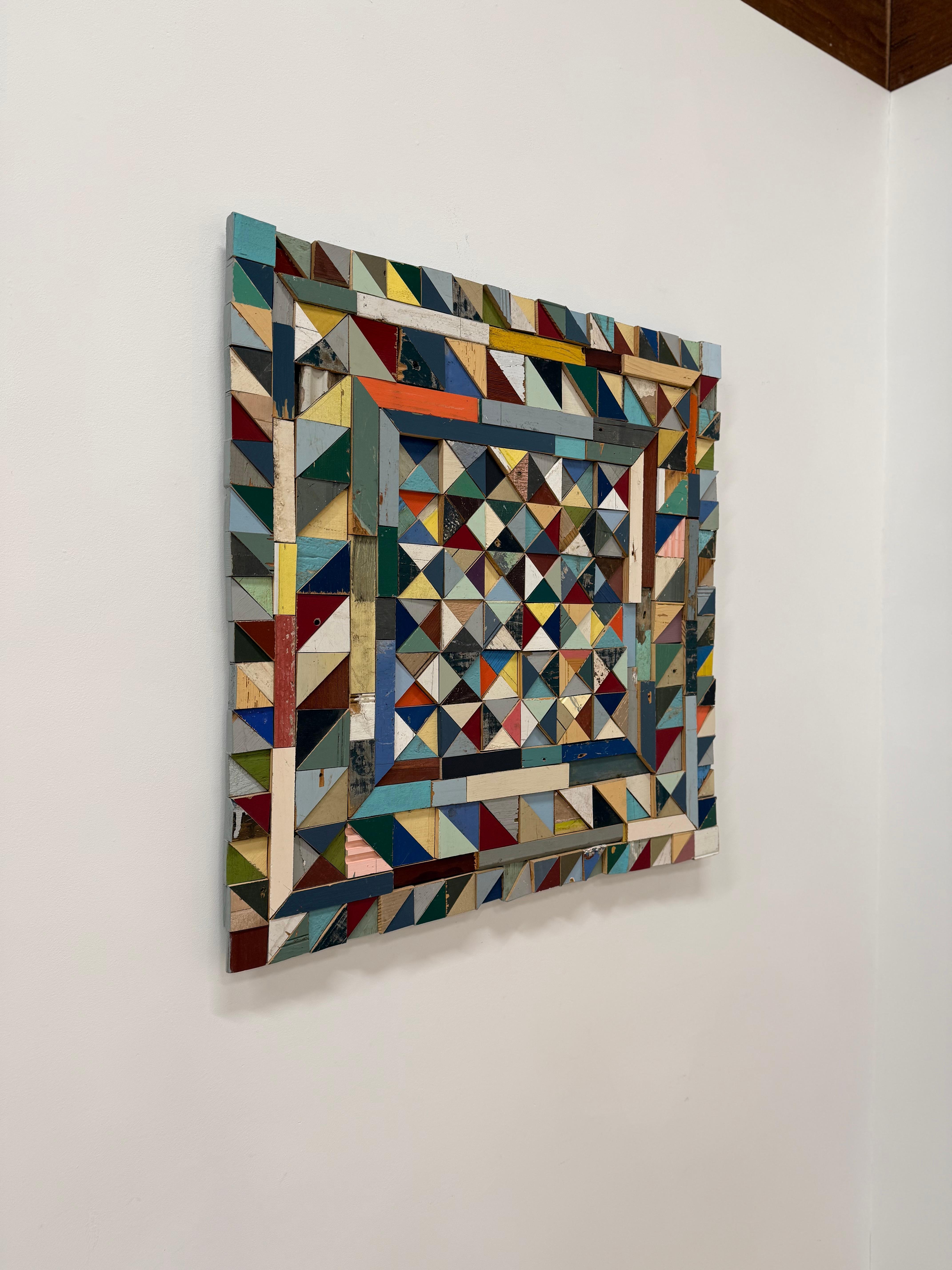 Sculpture murale saisissante composée de bois de récupération, Rounding the Corner illustre la fusion de l'artisanat, de la mémoire et de la résilience propre à Laura Petrovich-Cheney. S'inspirant des traditions du quilting et du design textile,