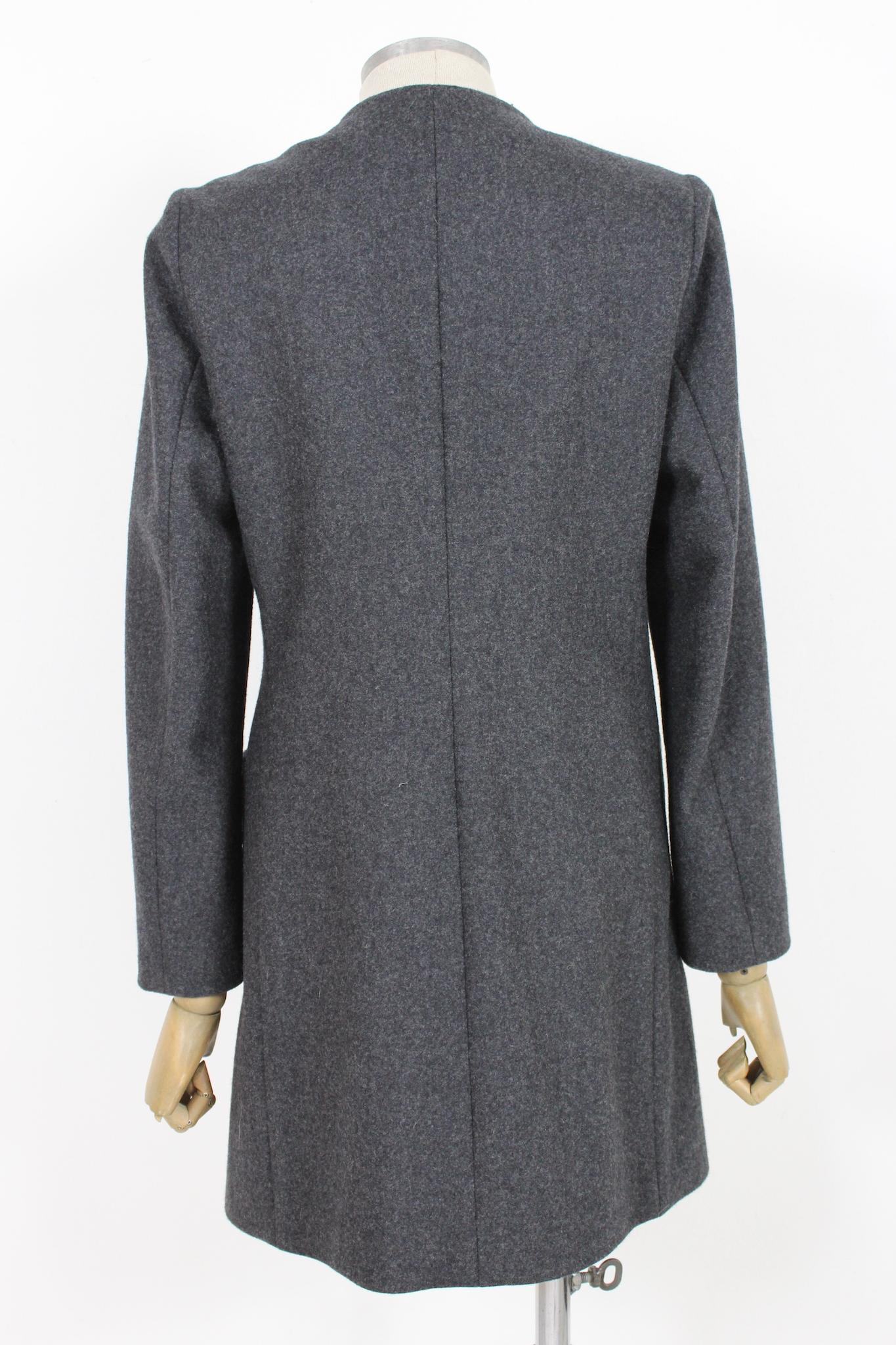 Cappotto classico grigio Laura Urbinati anni 2000. Modello svasato, chiusura con bottone a clip nascosto, girocollo, tasche laterali. Tessuto 95% lana, 5% poliammide, foderato internamente. Prodotto in Italia.

Taglia: 40 It 6 Us 8 Uk

Spalla: 42