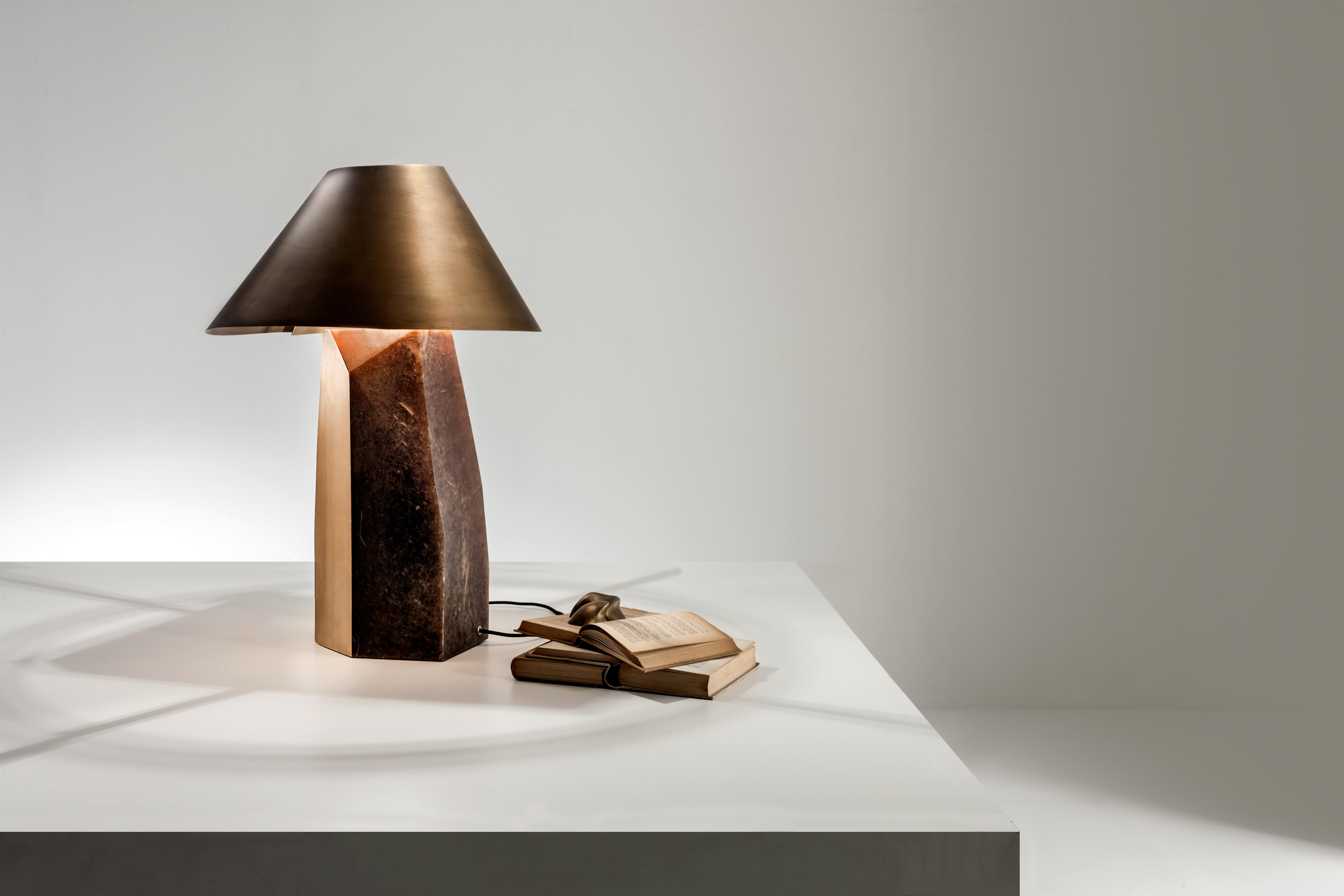 Sculptural table lamp with Alabaster base and burnished brass lampshade. Polyhedral base with a satin brass side and lampshade with a rounded shape and an unusual cutting detail.

FINISH:
Alabaster and burnished brass

Ada is sculptural table lamp