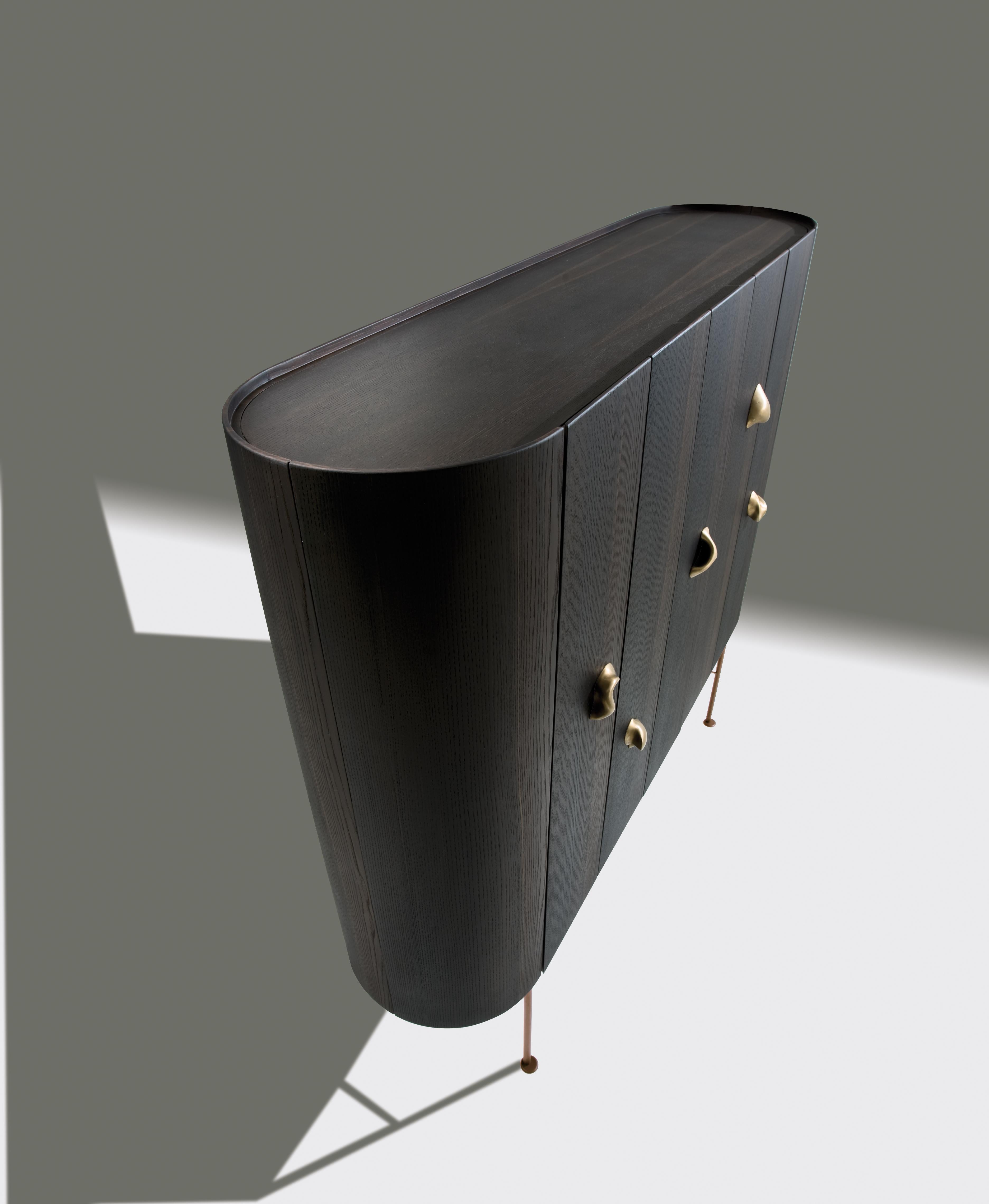 Storage unit in Siberian Ash wood with 7 hinged doors and curved sides. Satin brass base and 5 Sesel collection handles in cast bronze. Internally equipped with 8 drawers and shelves.

Collectionist design is inspired by the 