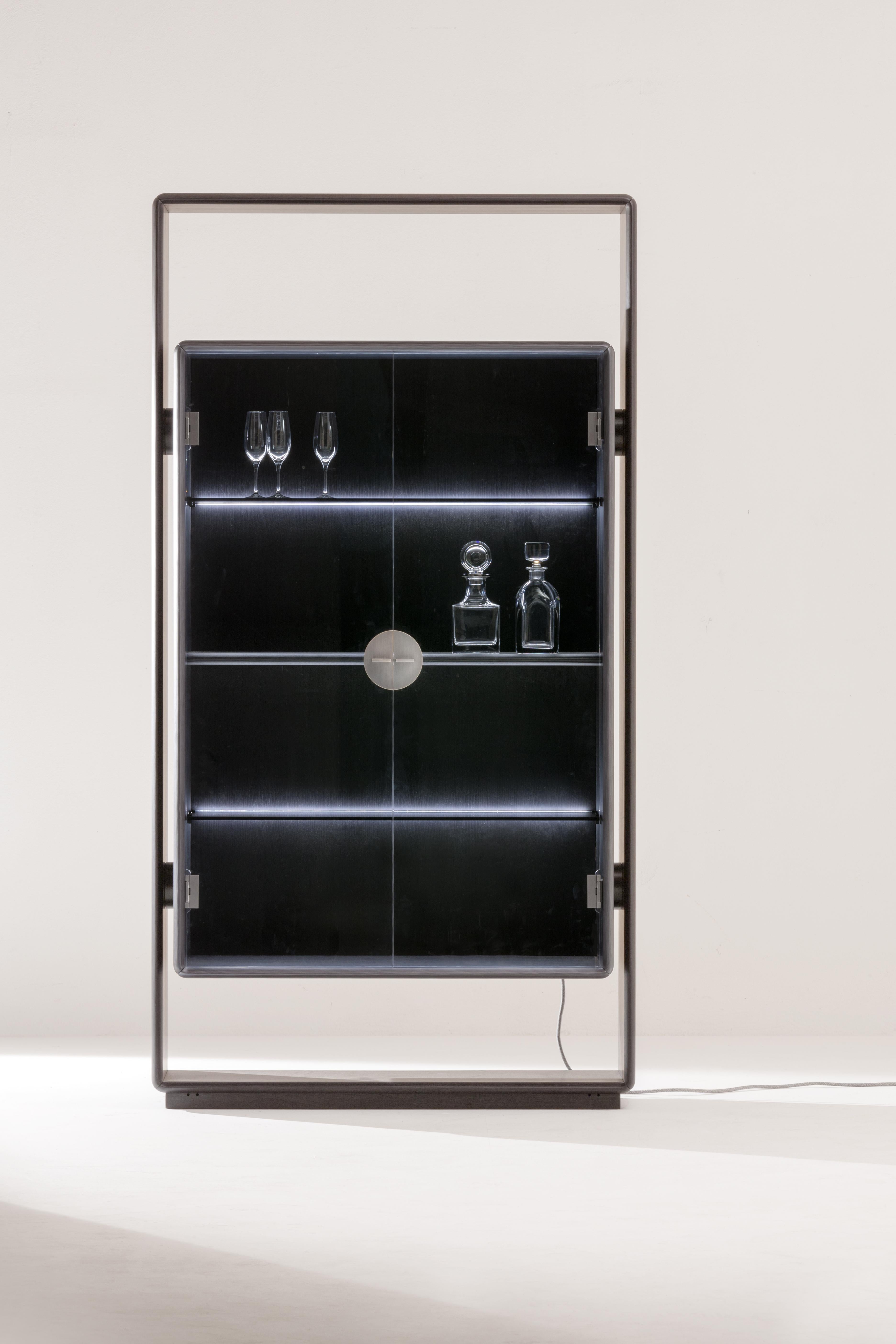 Tall storage unit with 2 hinged doors. Internally equipped with 2 glass shelves with LED lighting and 1 wooden shelf. Structure in black-dyed wood, doors in glass. Handle in burnished brass. Container and interiors in dyed wood Black AL1853.
2019