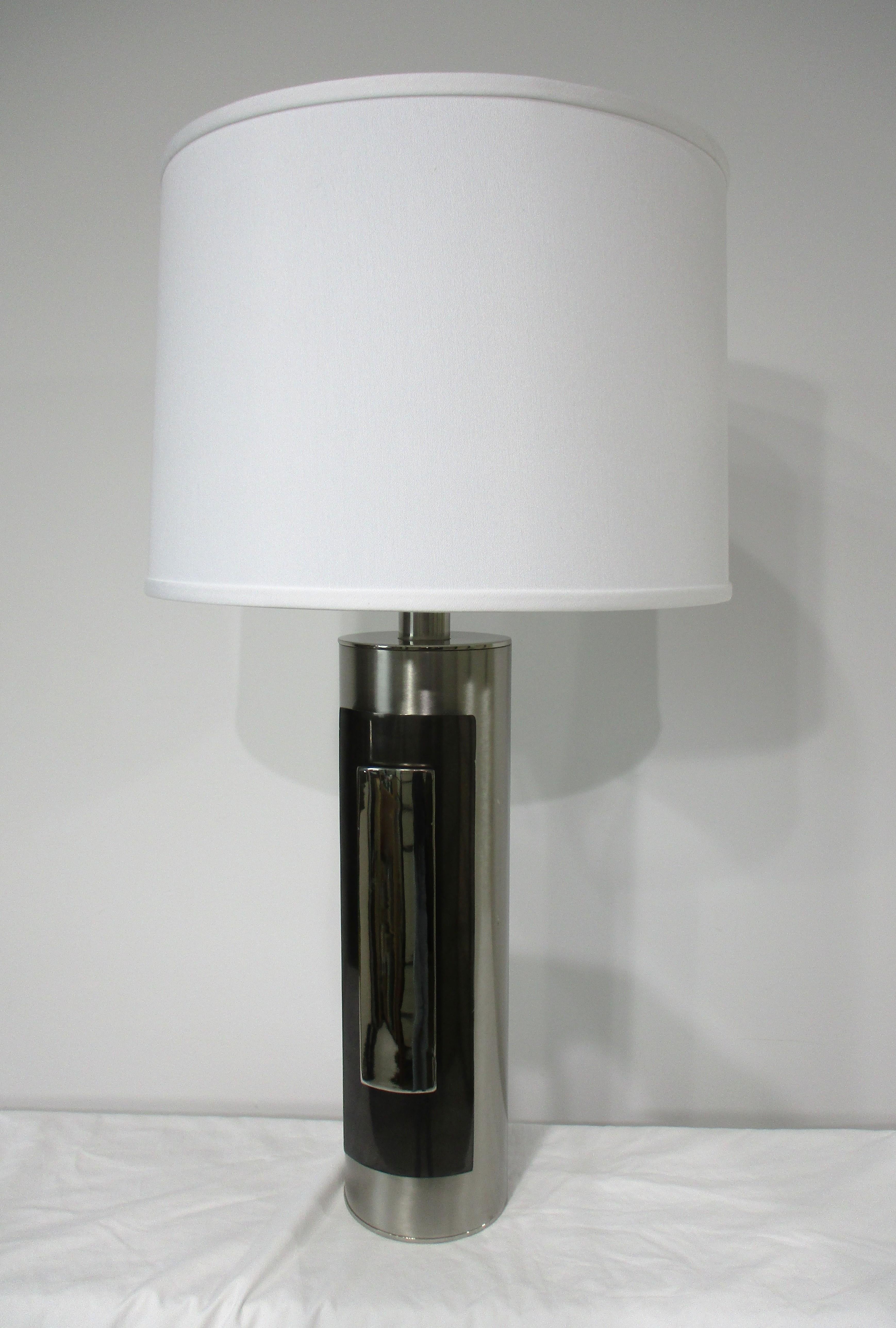 A very well crafted table lamp with brushed stainless steel body having polished chrome and black chrome accents . Topped with a linen barrel shade this lamp has that luxurious vibe of the 1970's glamor period in which it was designed , retains the