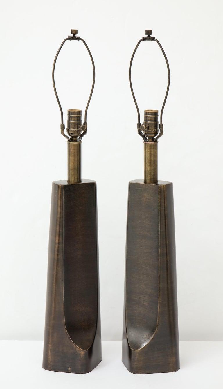 Paire de lampes modernistes sculpturales en bronze vieilli au profil brutal et élancé. Recâblage professionnel pour une utilisation aux Etats-Unis. Ampoules de 100W max.