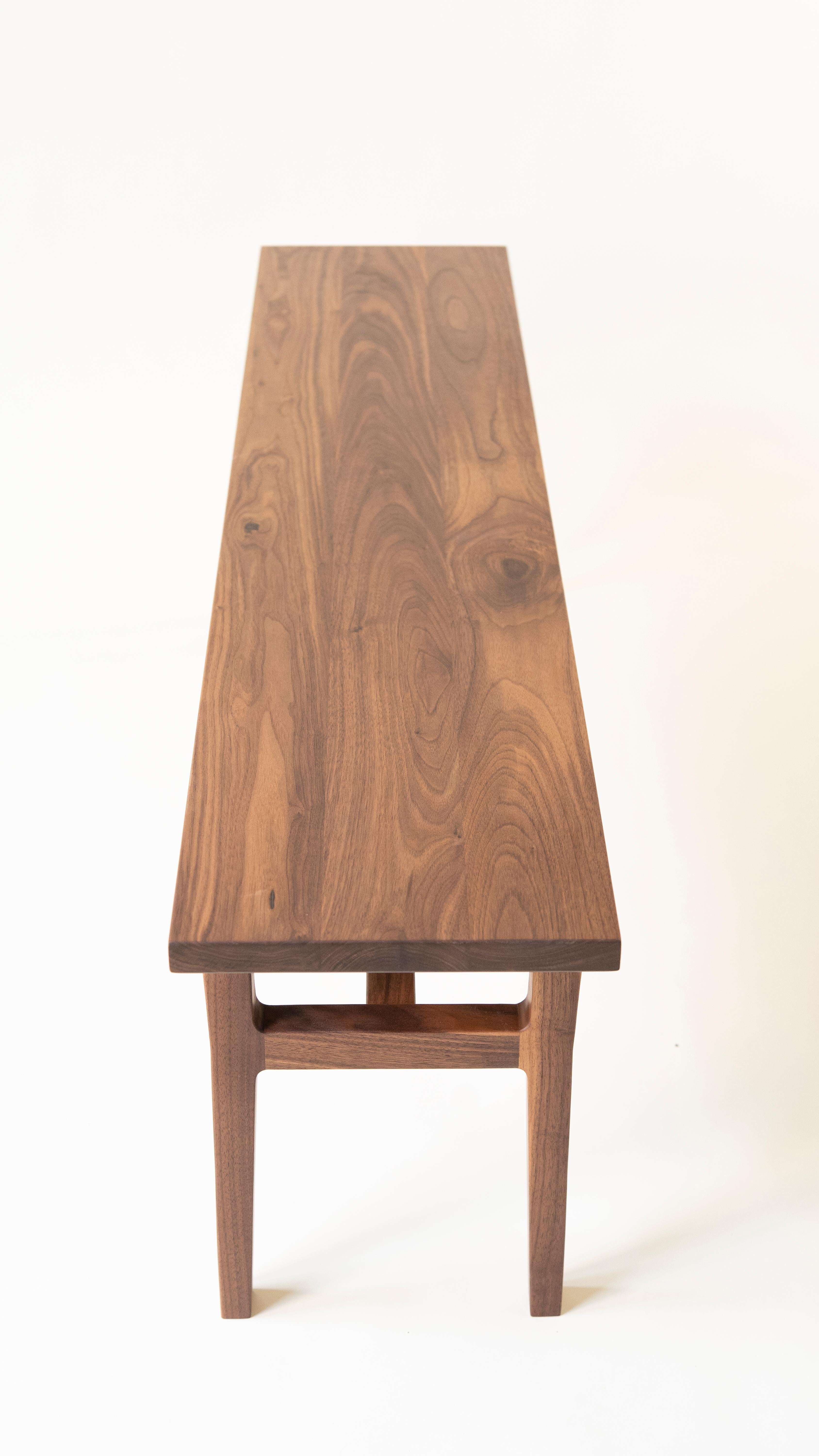 Inspiriert von der dänischen Einfachheit und dem organischen Design, zeichnet sich die Lorbeerbank durch skulpturale Beine, schlichte Winkel und robuste Tischlerarbeiten aus. Die Bank ist aus nachhaltigem Nussbaumholz gefertigt, wobei jedes